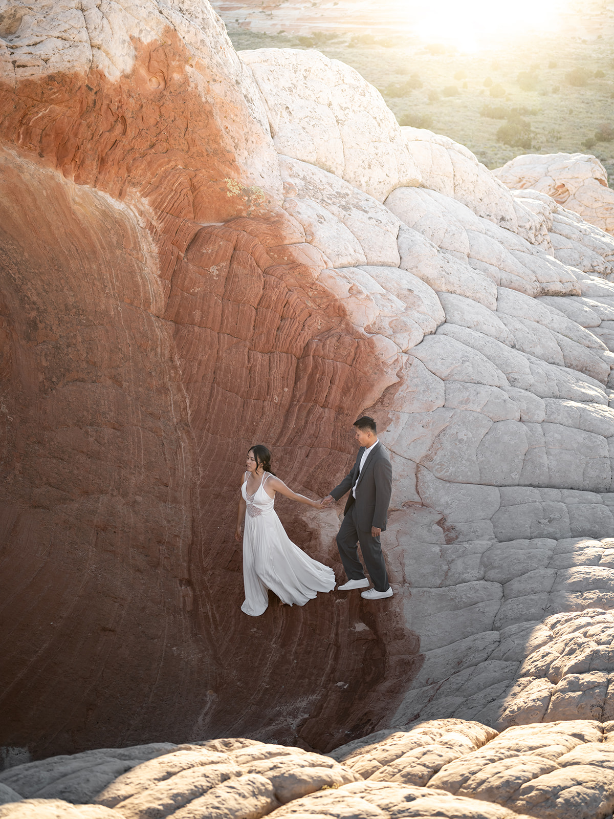 Couple crossing from white rocks to red rocks in White Pocket Arizona during their Elopement 