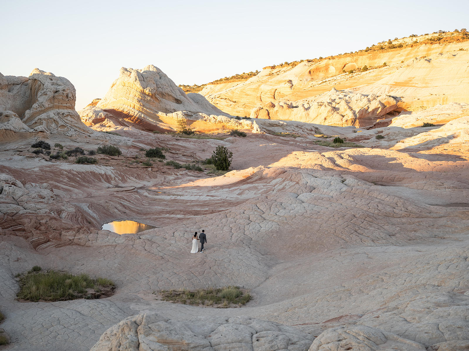 Couple walking through the vast sandstone dunes during their White Pocket Arizona Elopement 