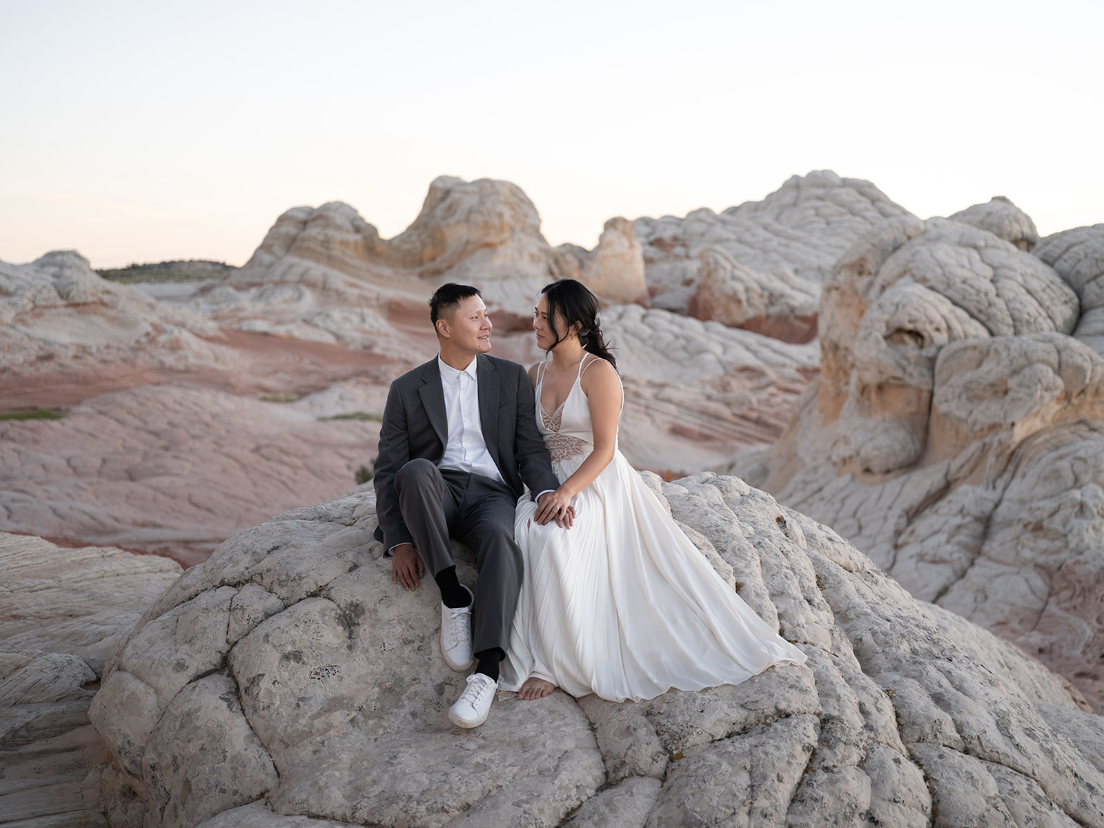 Couple setting on sandstone formations during golden hour in White Pocket, Arizona 
