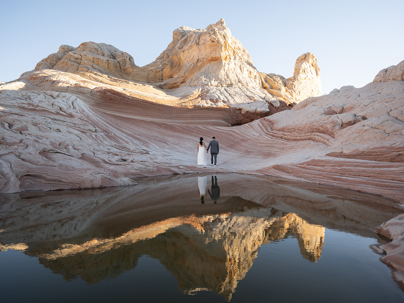 Couple standing in front of a reflection pool during their white pocket arizona elopement 