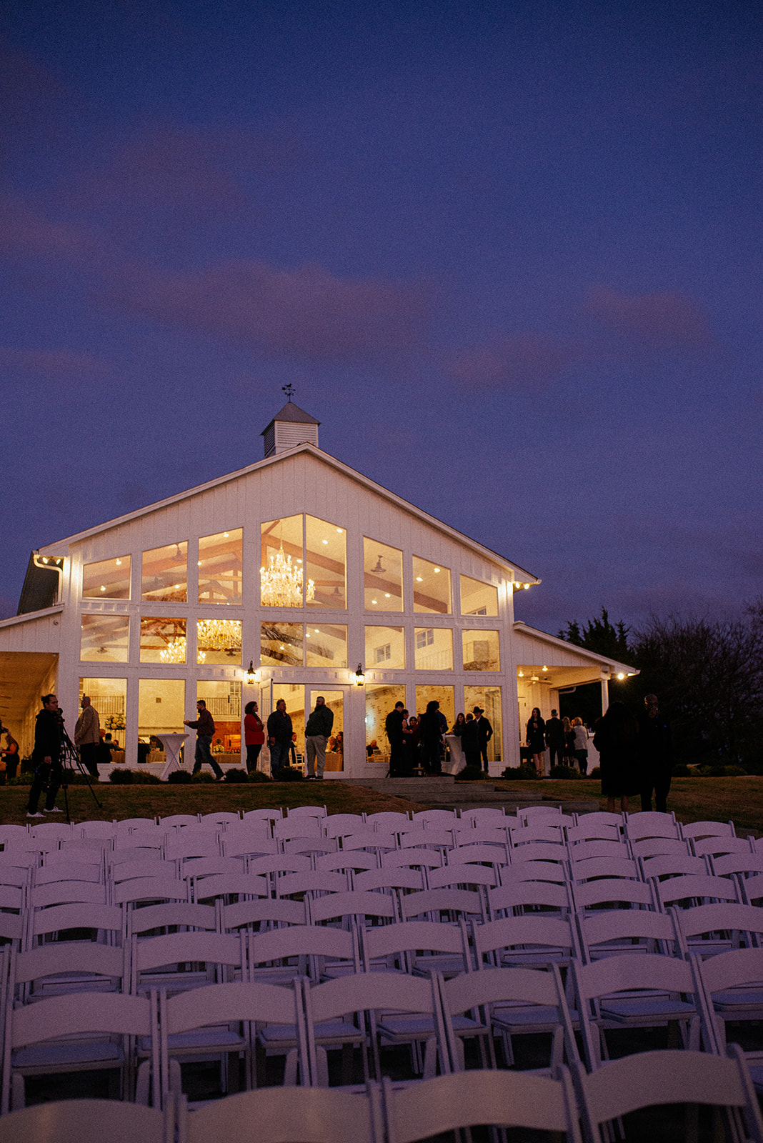 A nighttime photo of Firefly Gardens wedding venue and its wall of glass windows.
