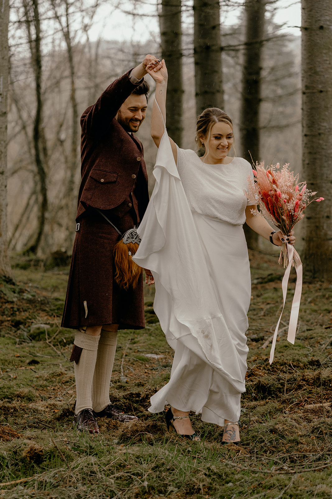 bride and groom practice their first dance in scottish woodland