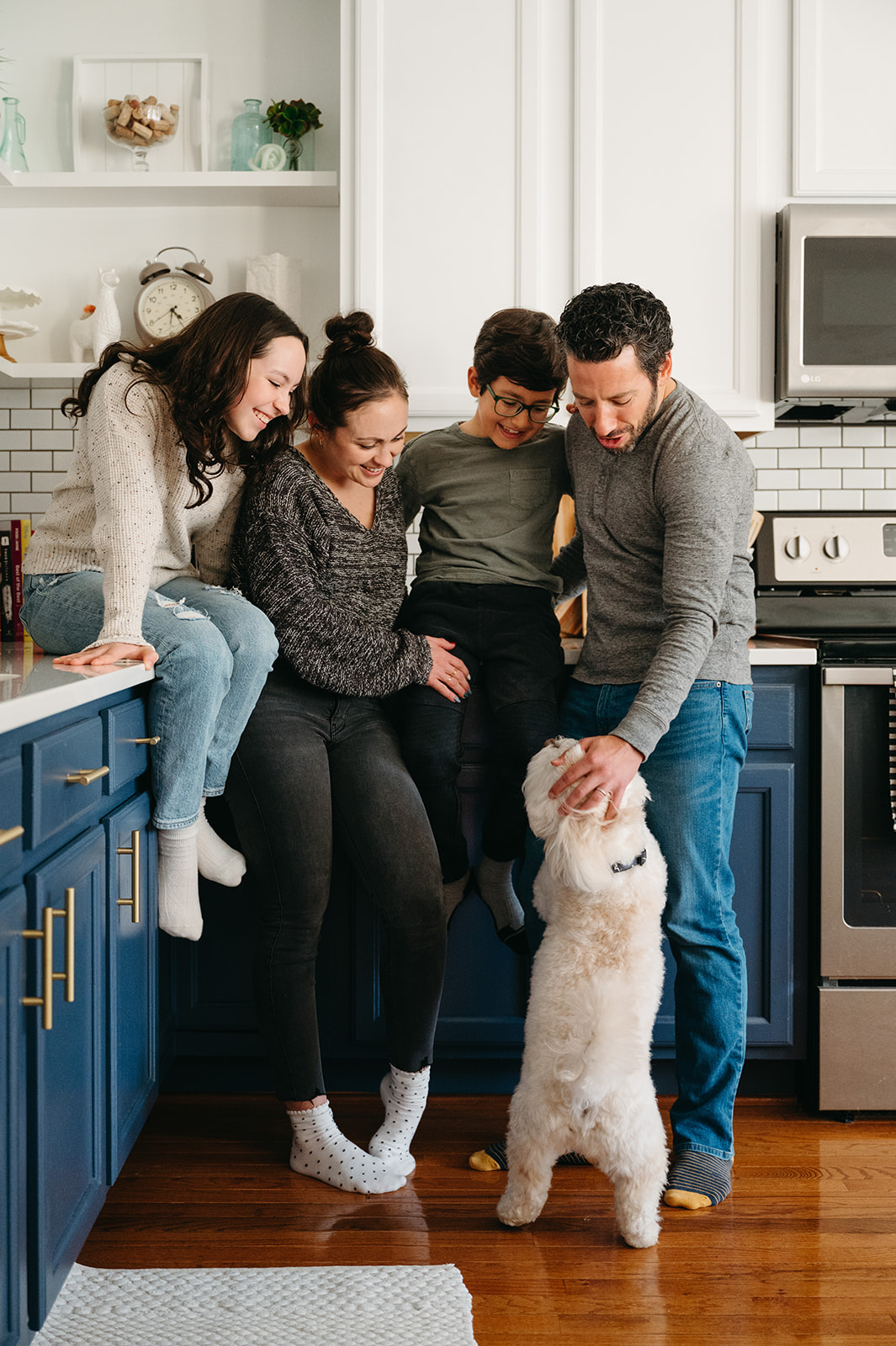 Family of 4 loving on their dog in their kitchen 
