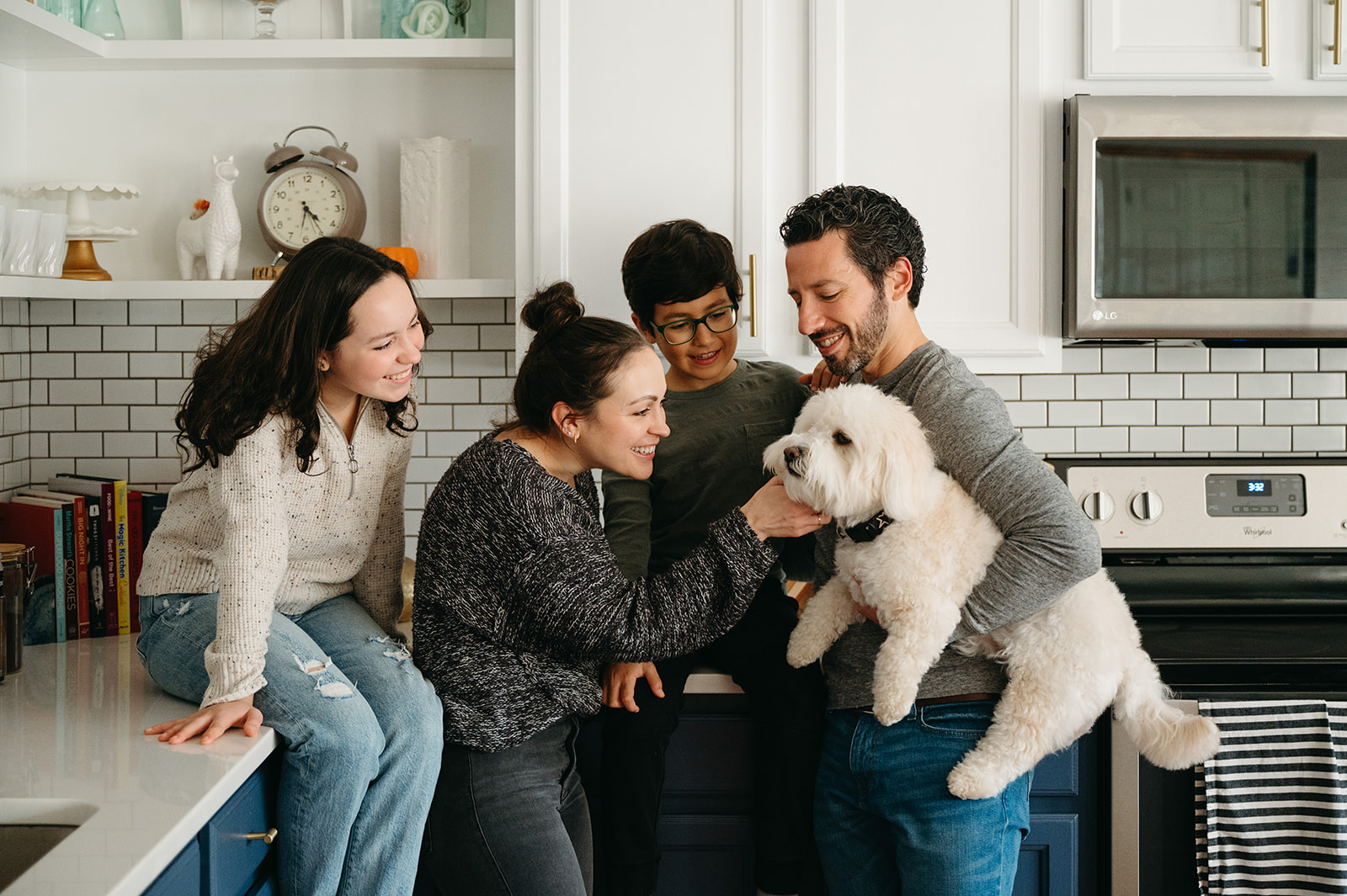 Family of 4 loving on their dog in their kitchen 