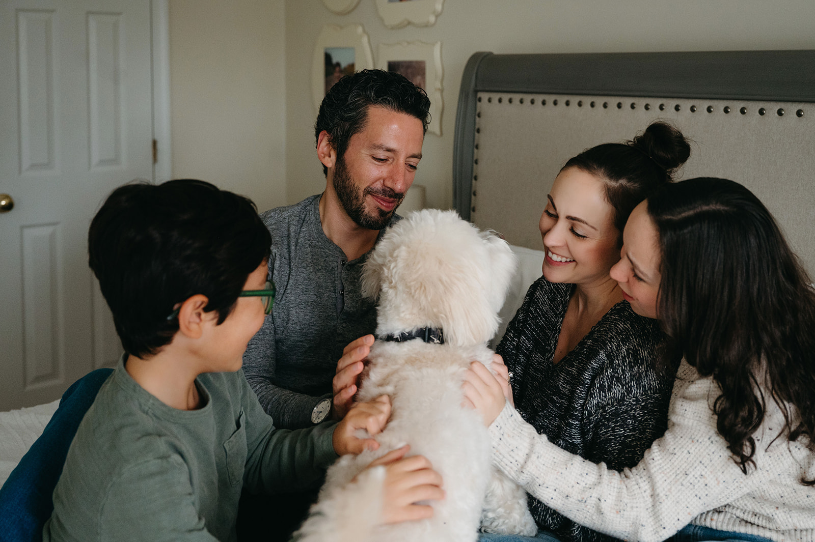 Family of four sitting on bed in their Pittsburgh home with dog