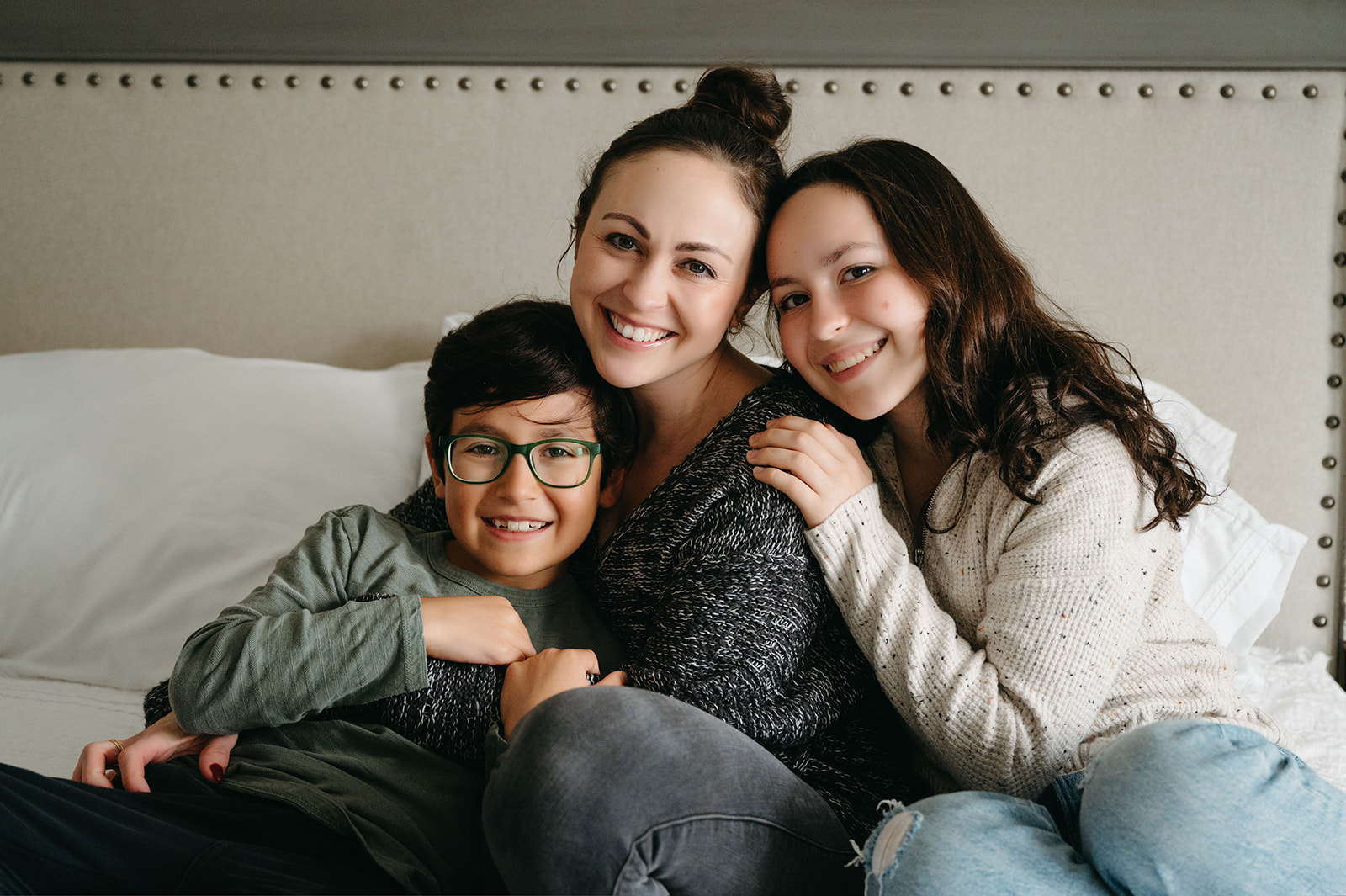 Loving family moment with mom, daughter, and son hugging on a bed