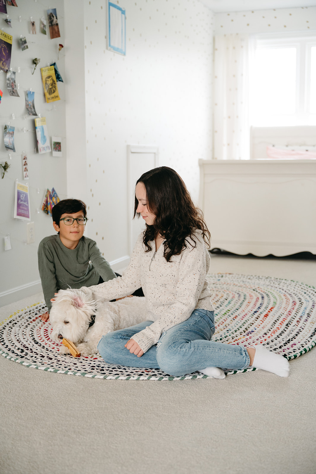 tween girl and younger brother hanging out in her room with her white dog 