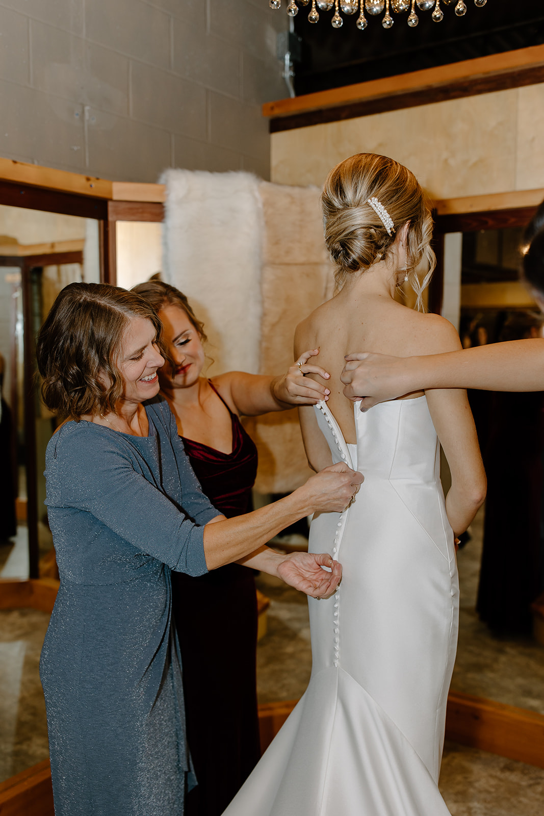 Mother zipping the bride's wedding dress