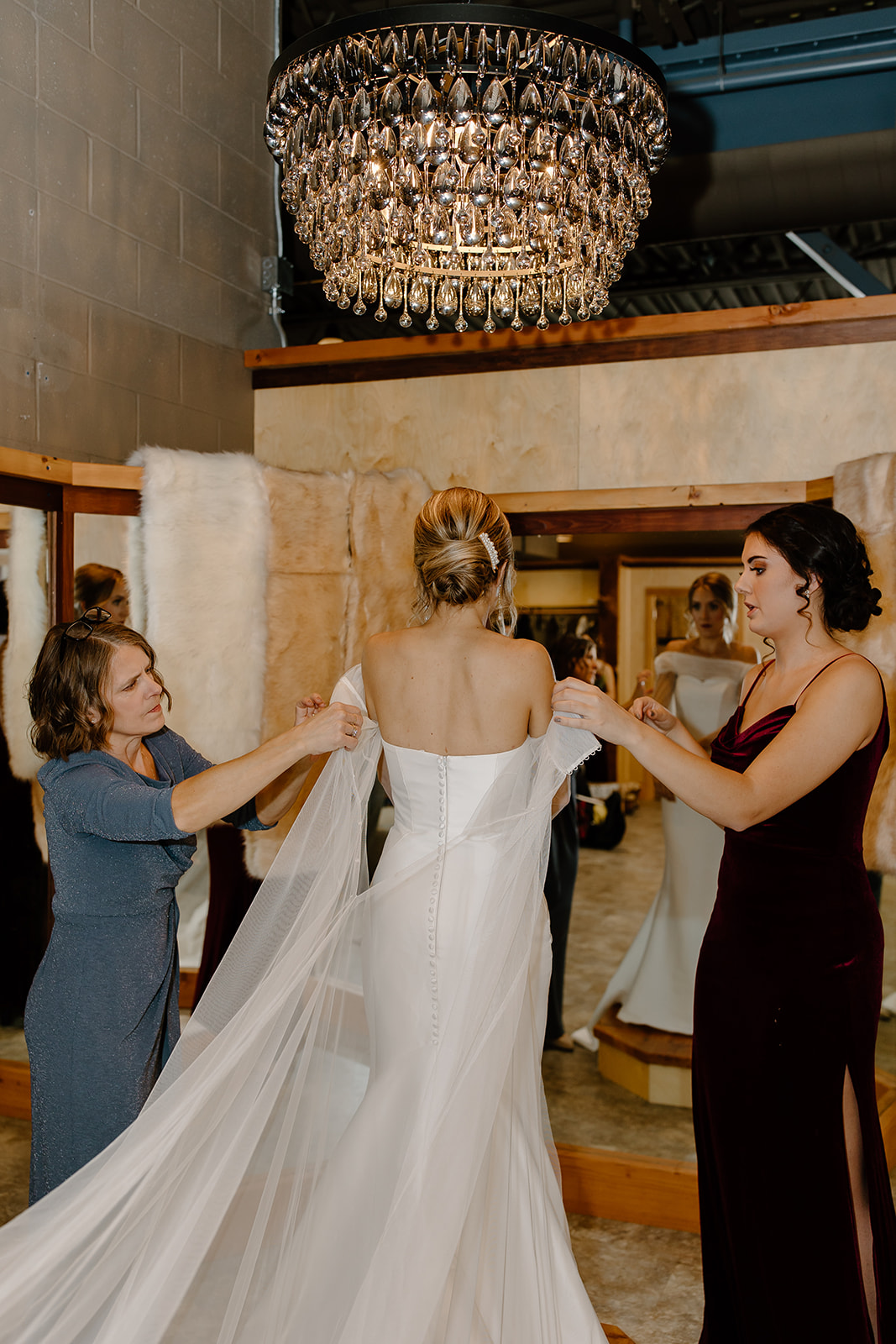 Mother and bridesmaid help a bride get dress
