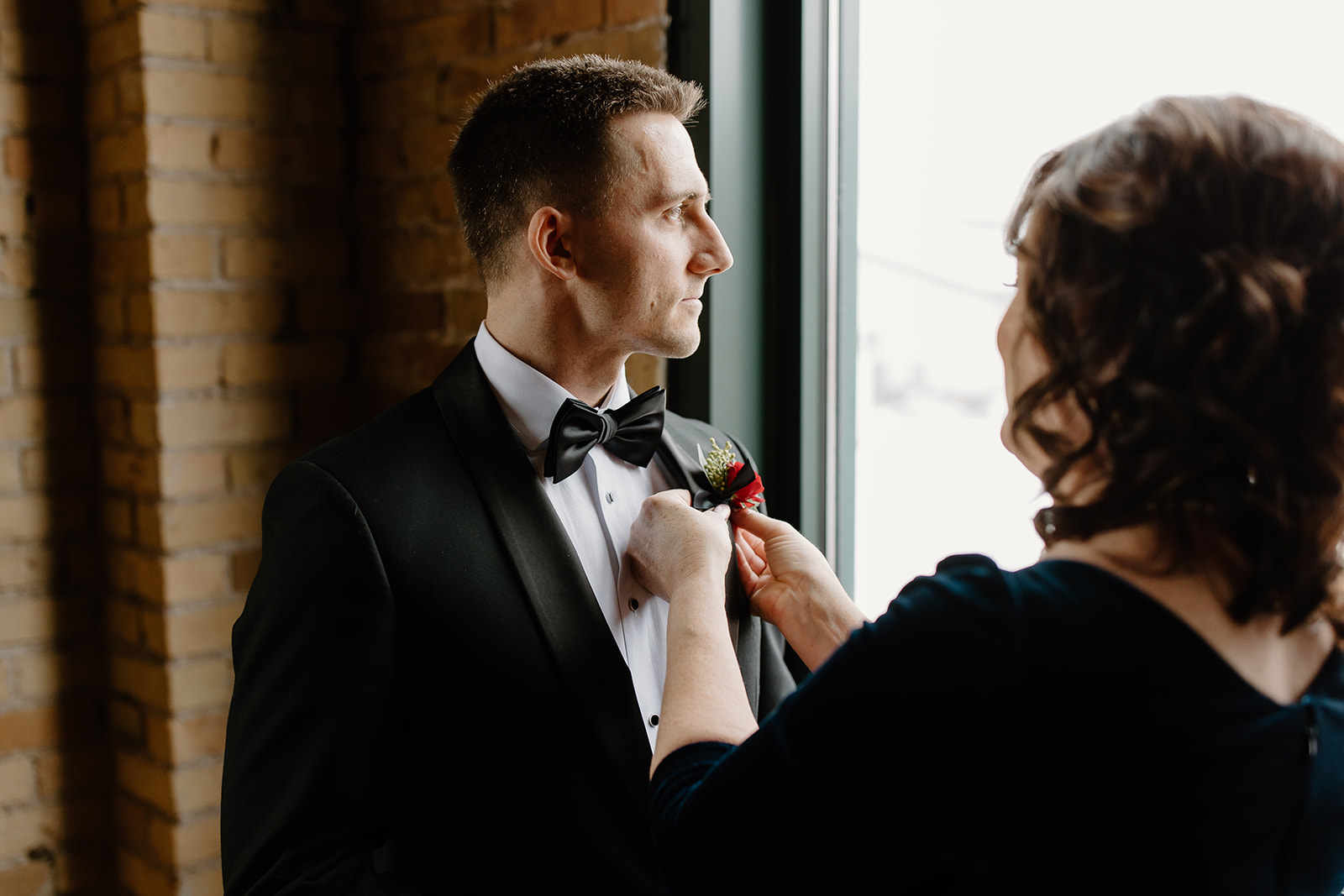Mother of the groom putting on groom's boutonniere 