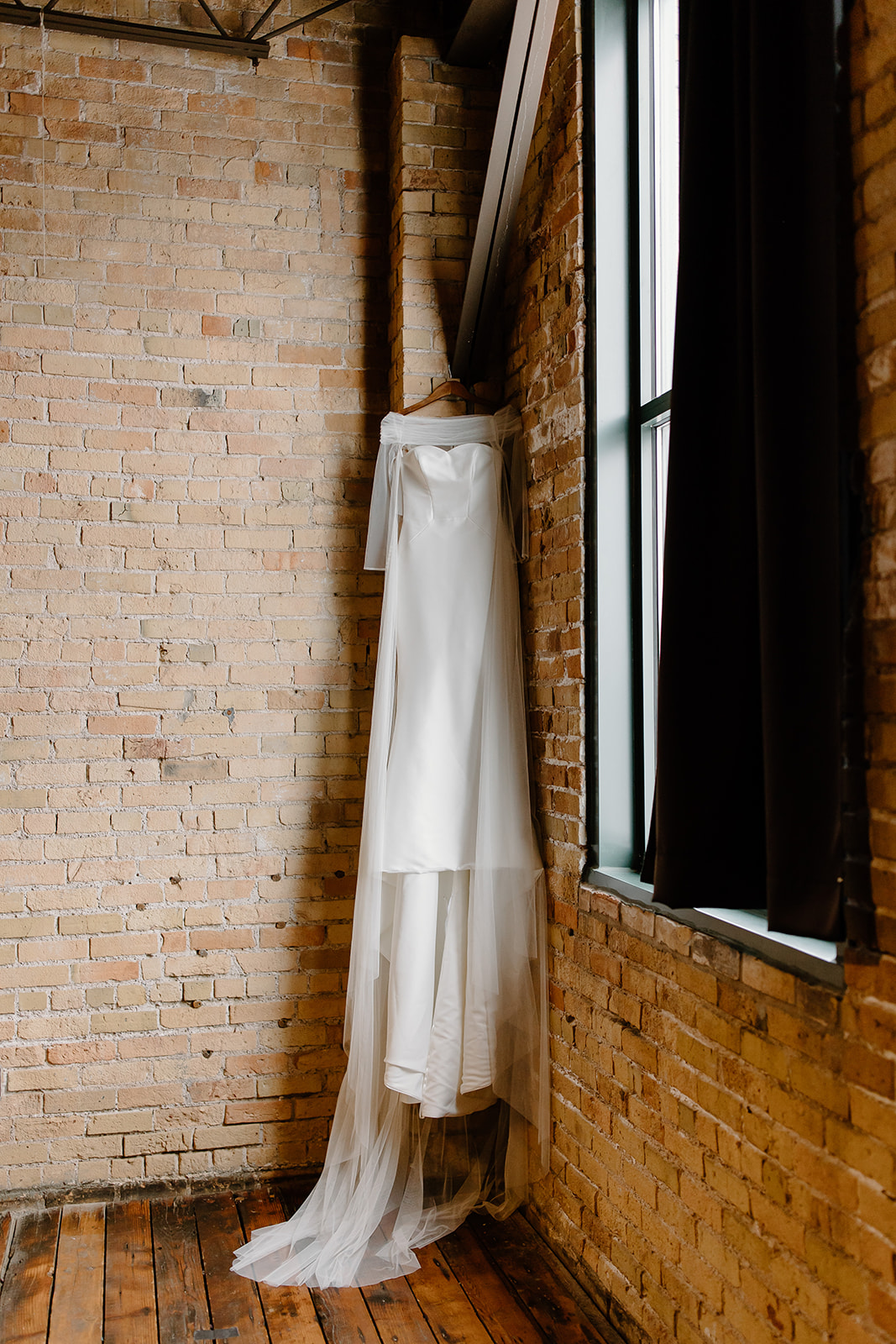 Wedding dress hanging in corner of brick wall