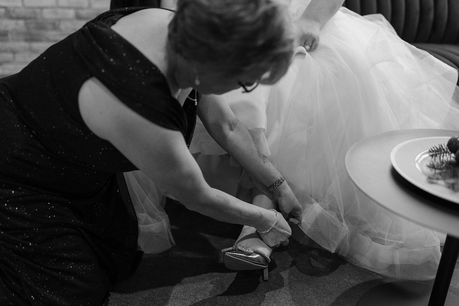 Mother of the bride putting bride's shoes on