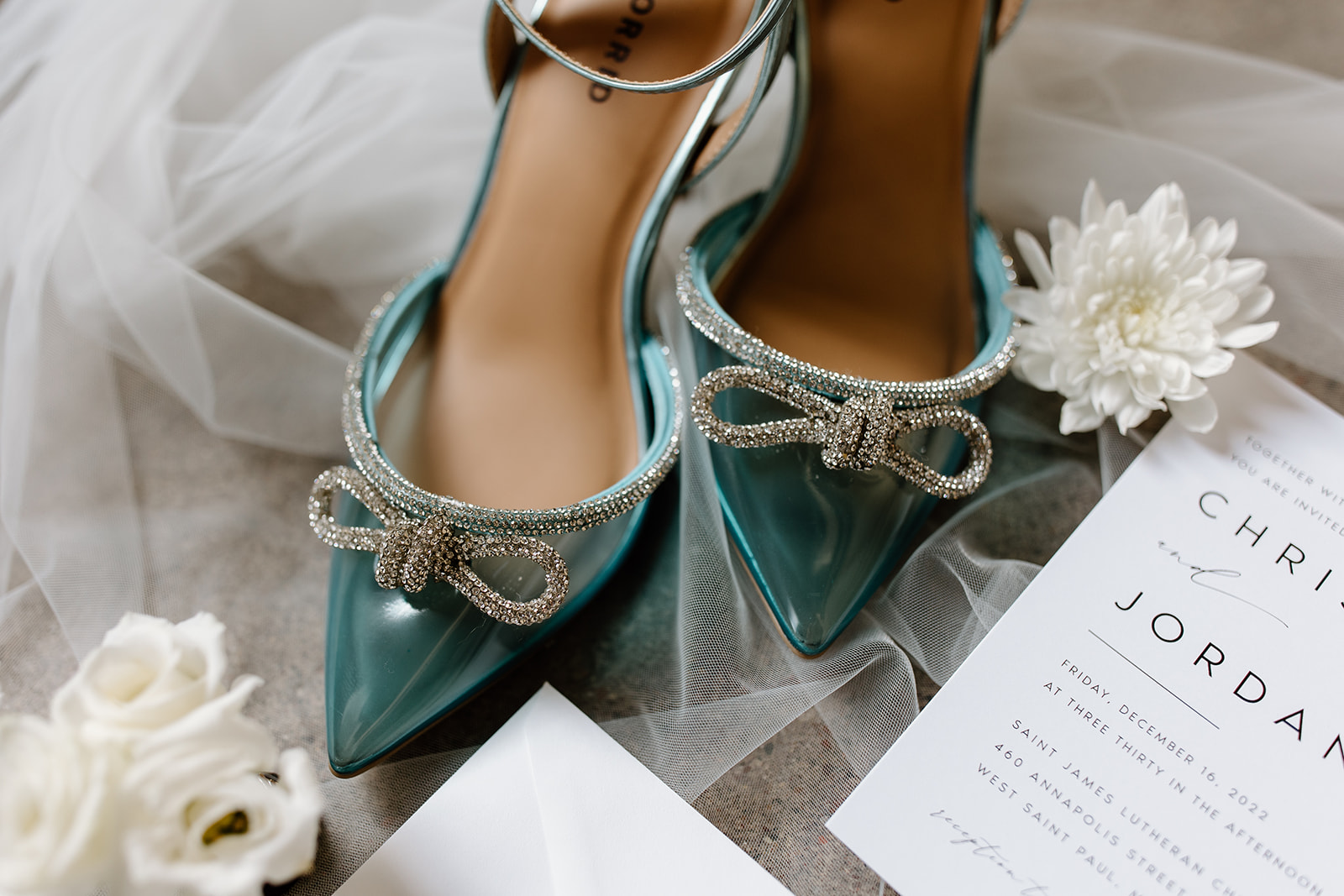 Flat lay of wedding invitations, jewelry, and shoes.