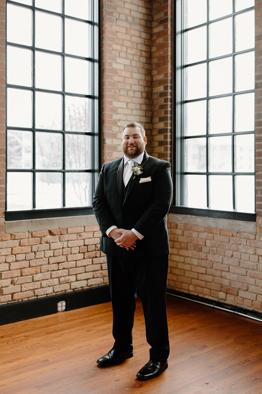 Groom smiling in front of windows