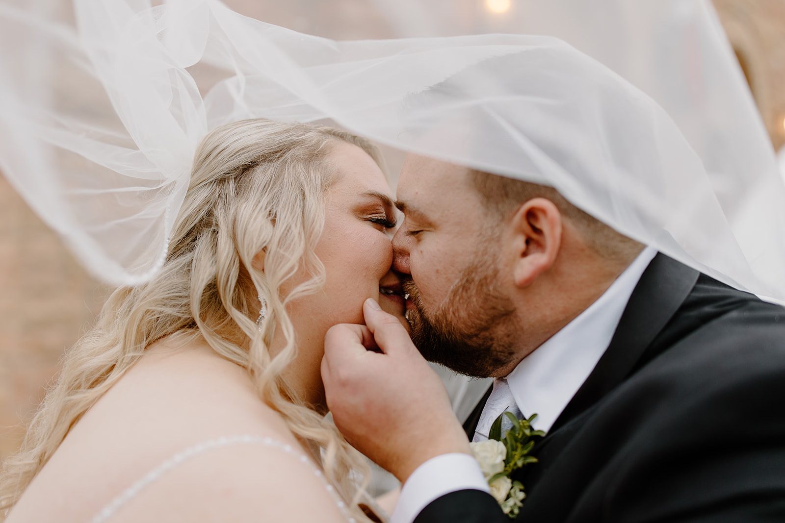 Bride and groom kissing under a veil
