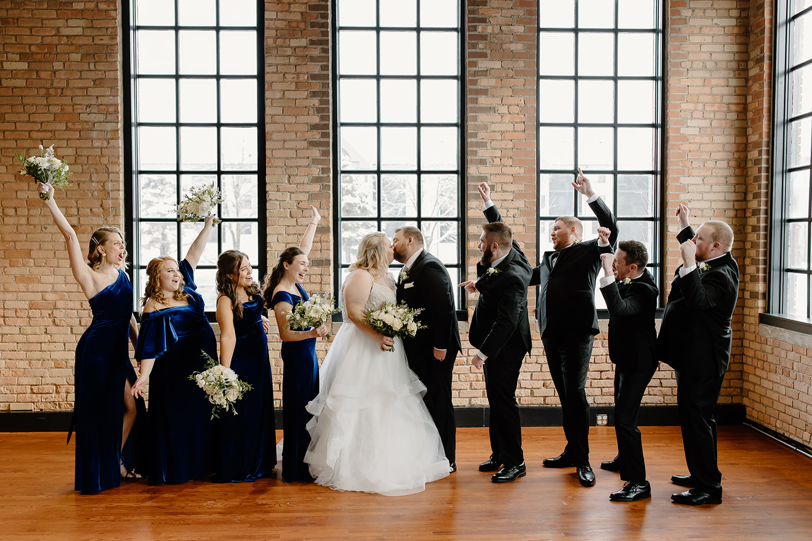 Wedding party cheering as bride and groom kiss