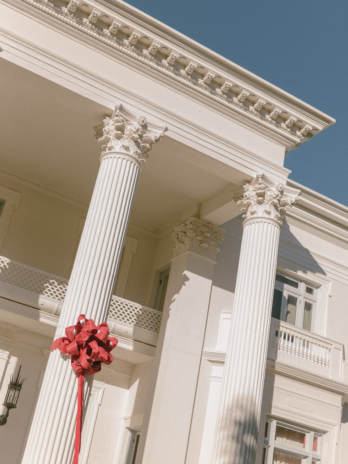 Big red bows flank the columns of the estately home