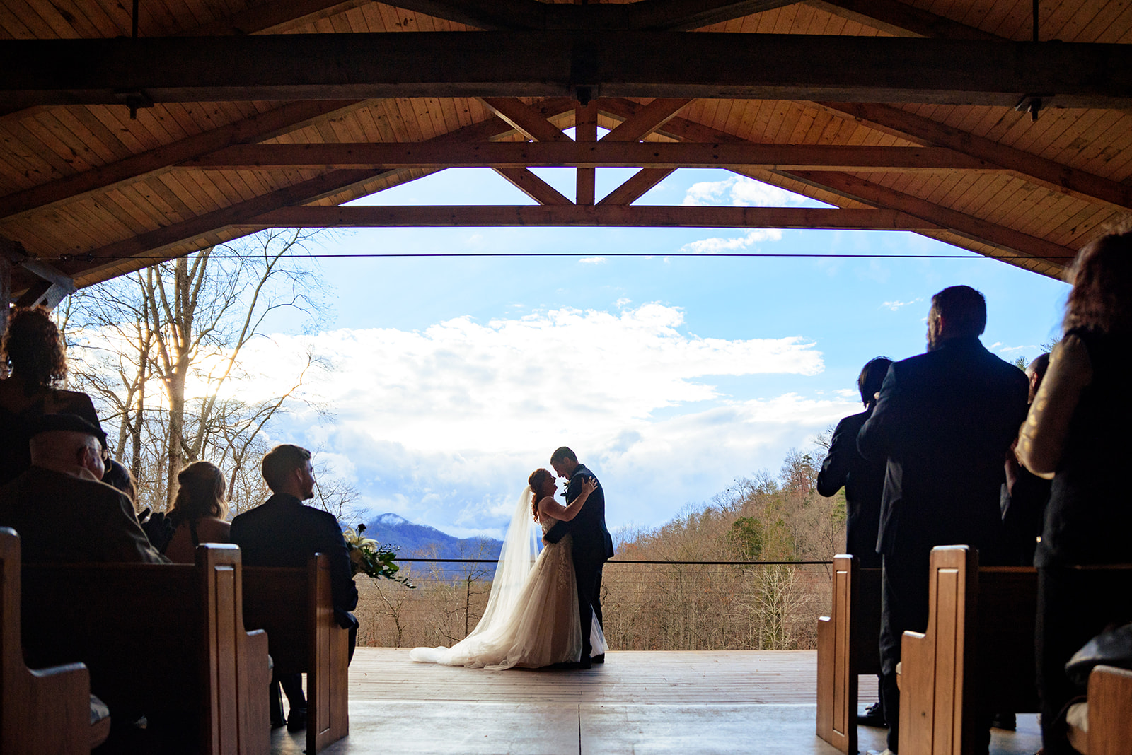 bride and groom sharing first kiss at parker mill with mountains in the background