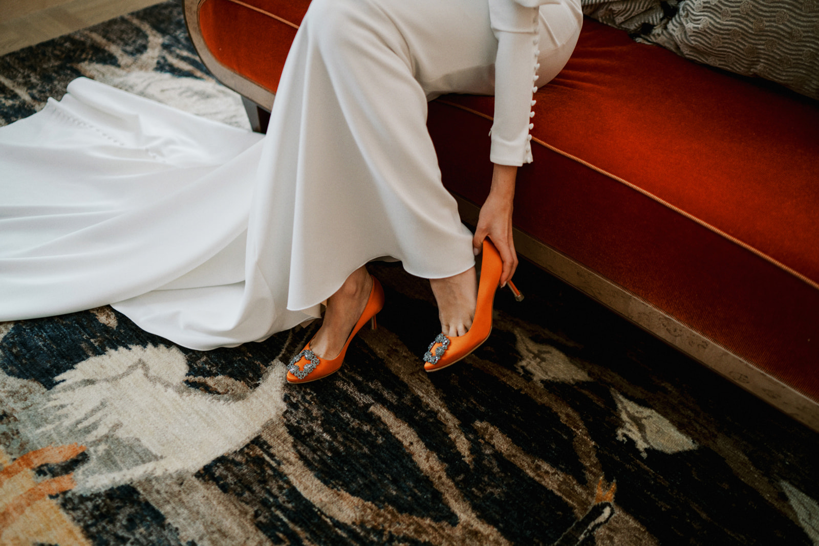 Detail photo of bride putting on her orange Manolo Blahnik for her city wedding