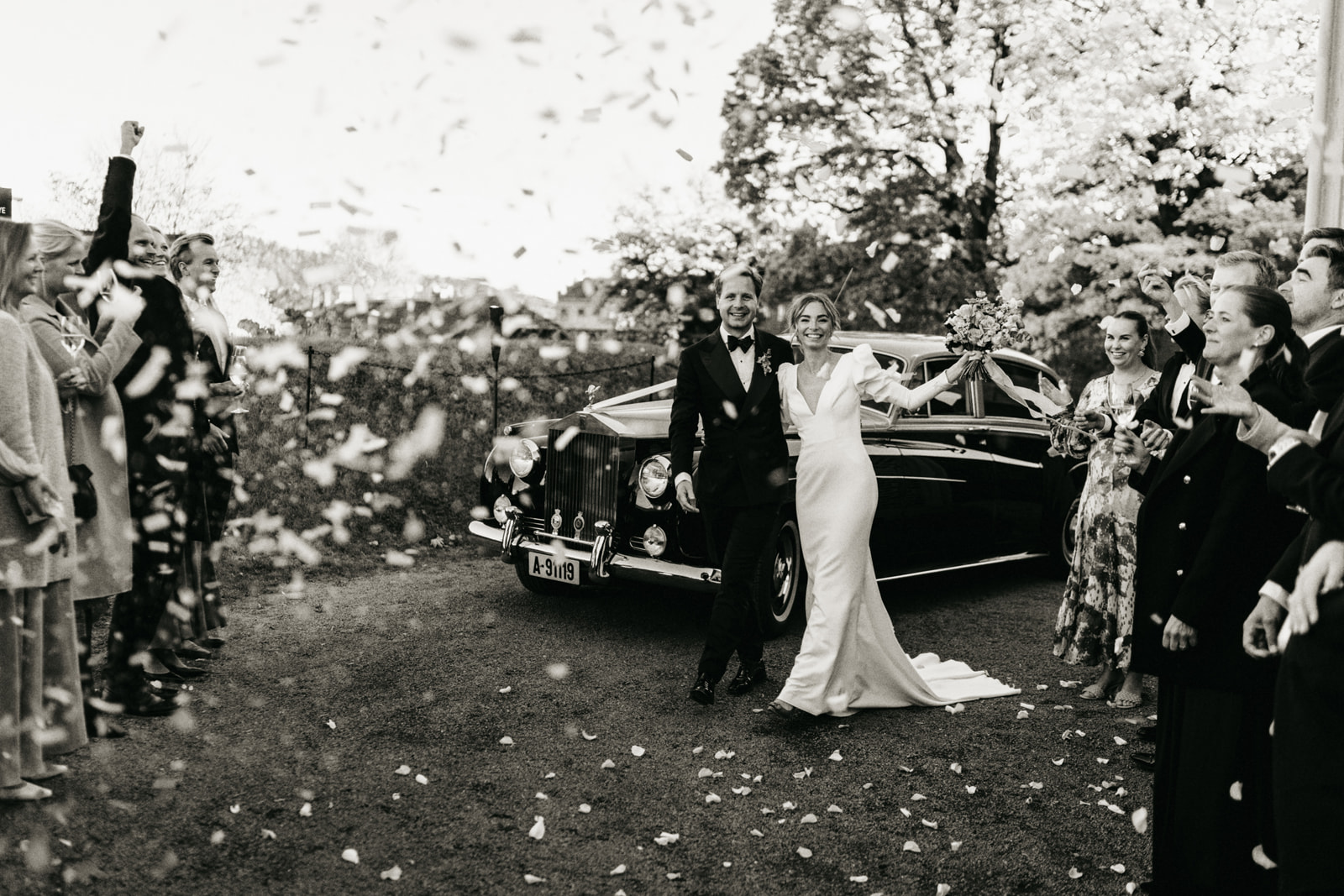 Konfetti øyeblikk med moderne brudepar foran veteranbil på bryllupsdagen