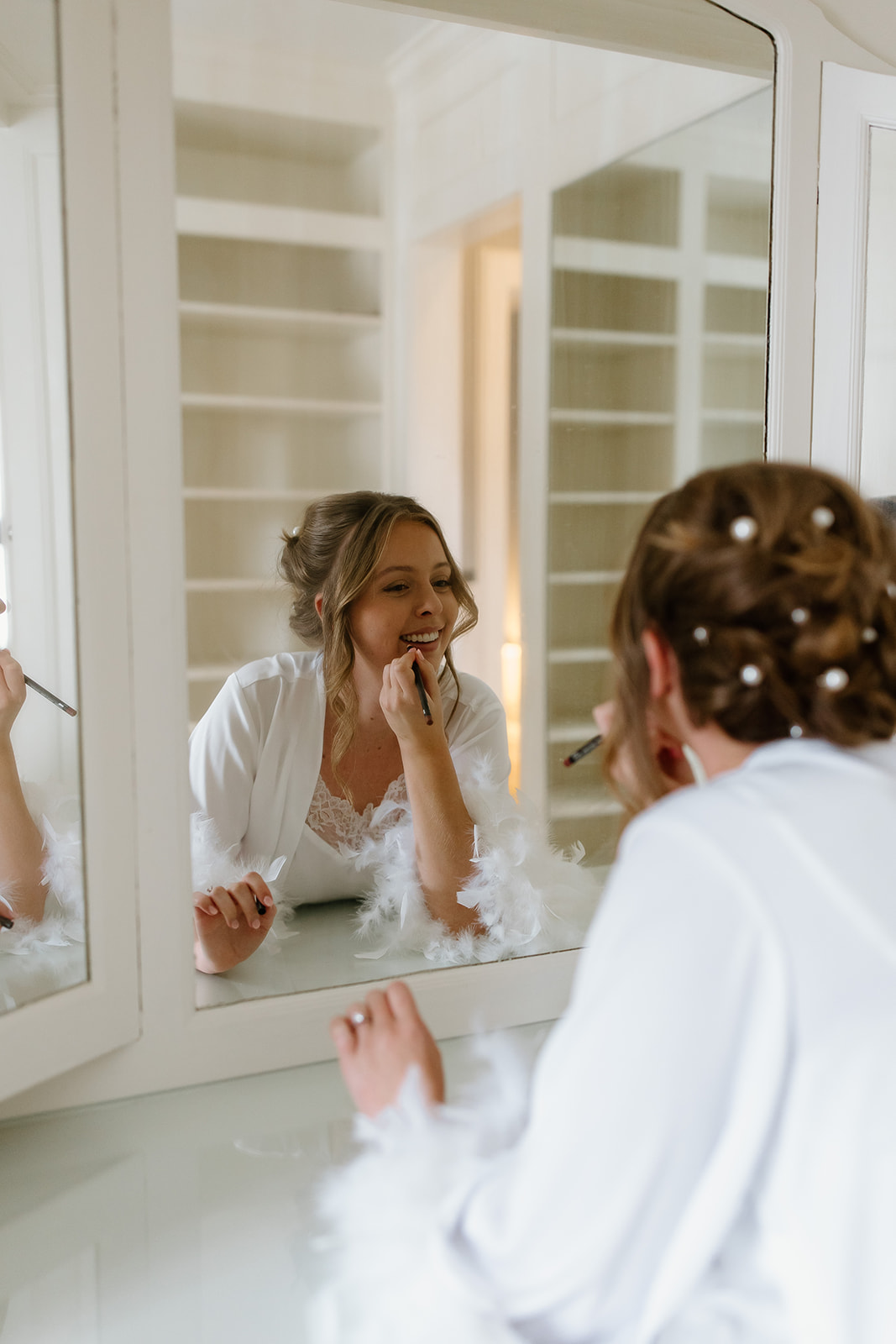 Bride putting lipstick on in mirror