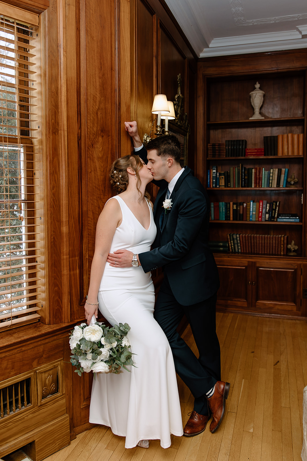 Bride and groom in front of bookshelf
