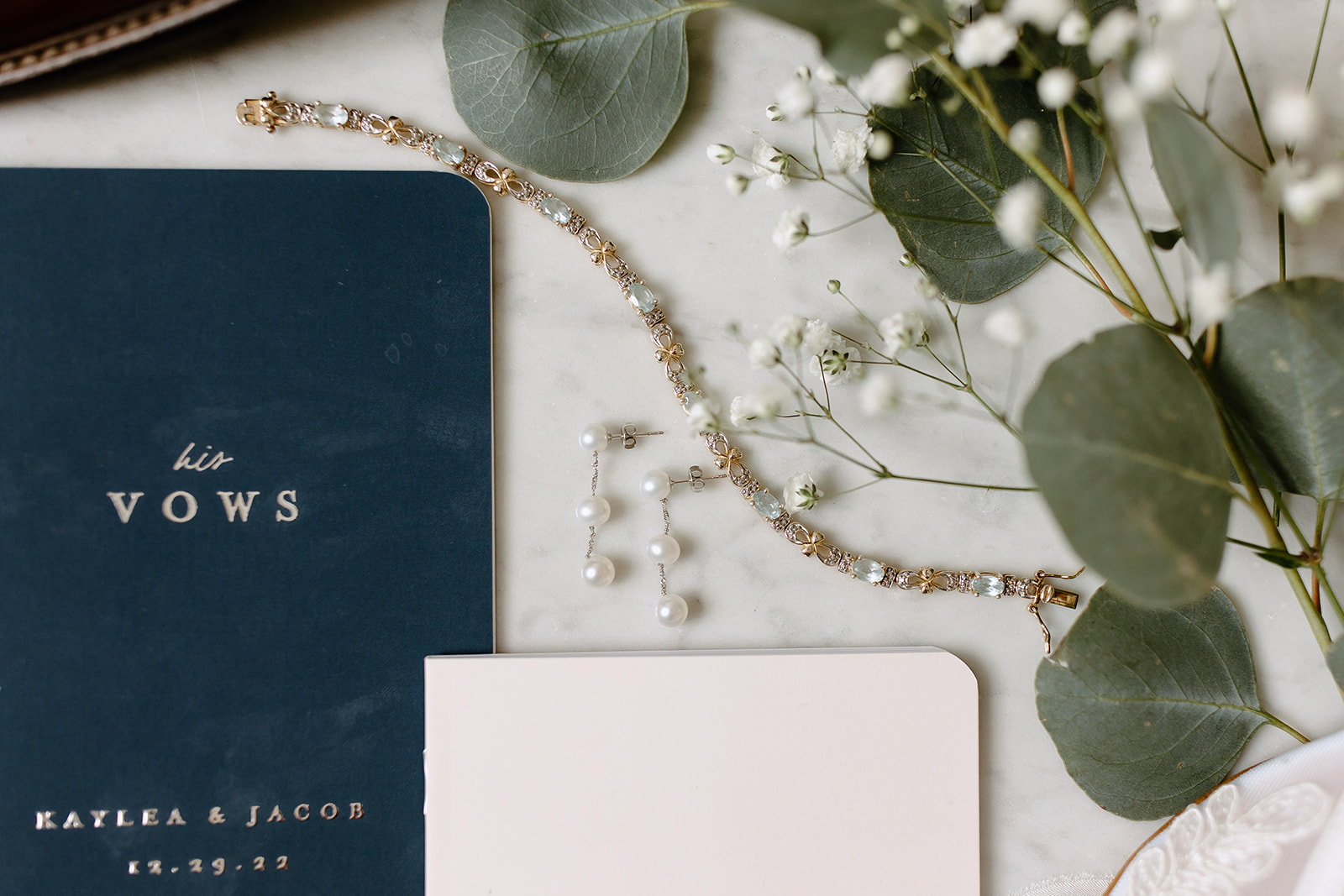 Flat lay of wedding vow books, jewelry, and shoes