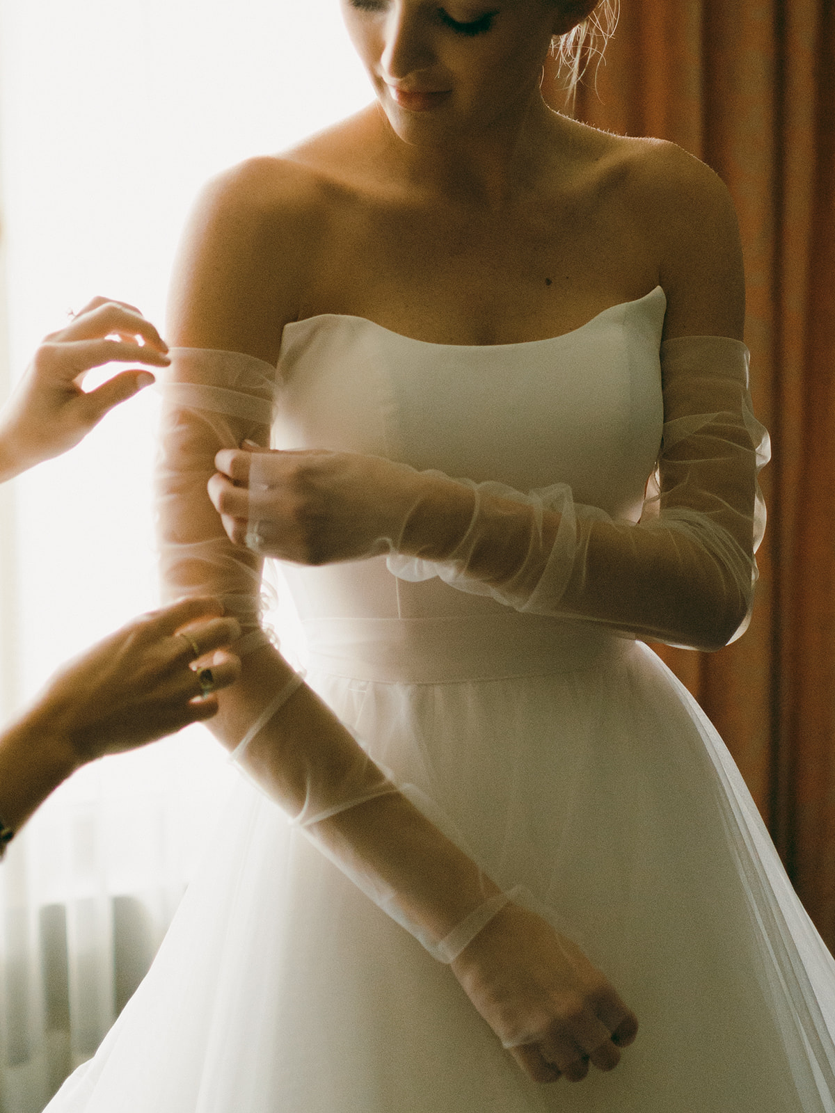 The bride adjusts the custom gloves with her custom convertible wedding gown.