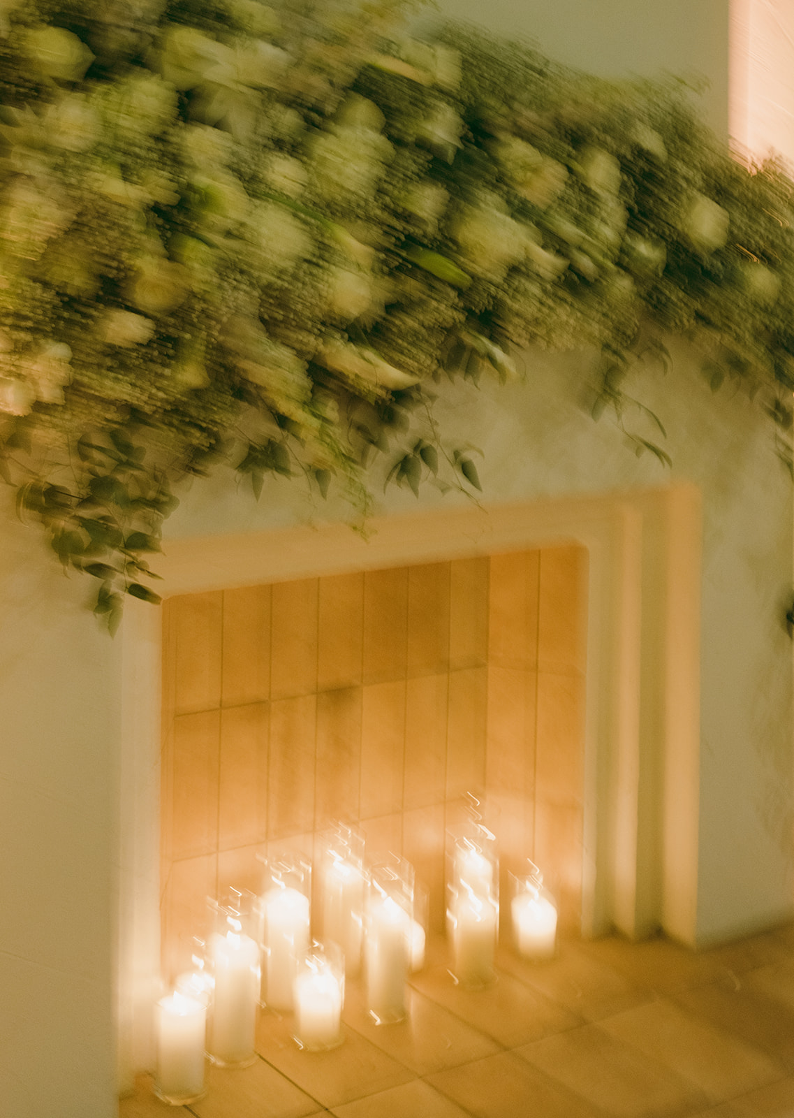 A floral installation decorates the Tuscan fireplace mantle with candlelight.