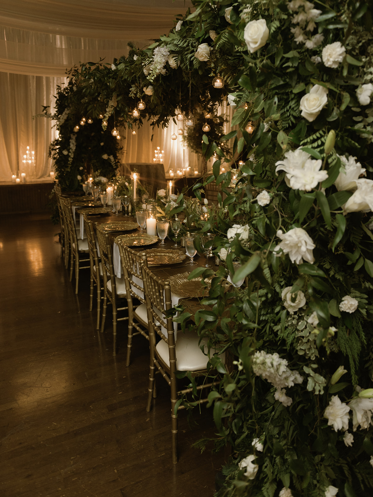 A floral arch encompasses the head table at the rehearsal dinner.