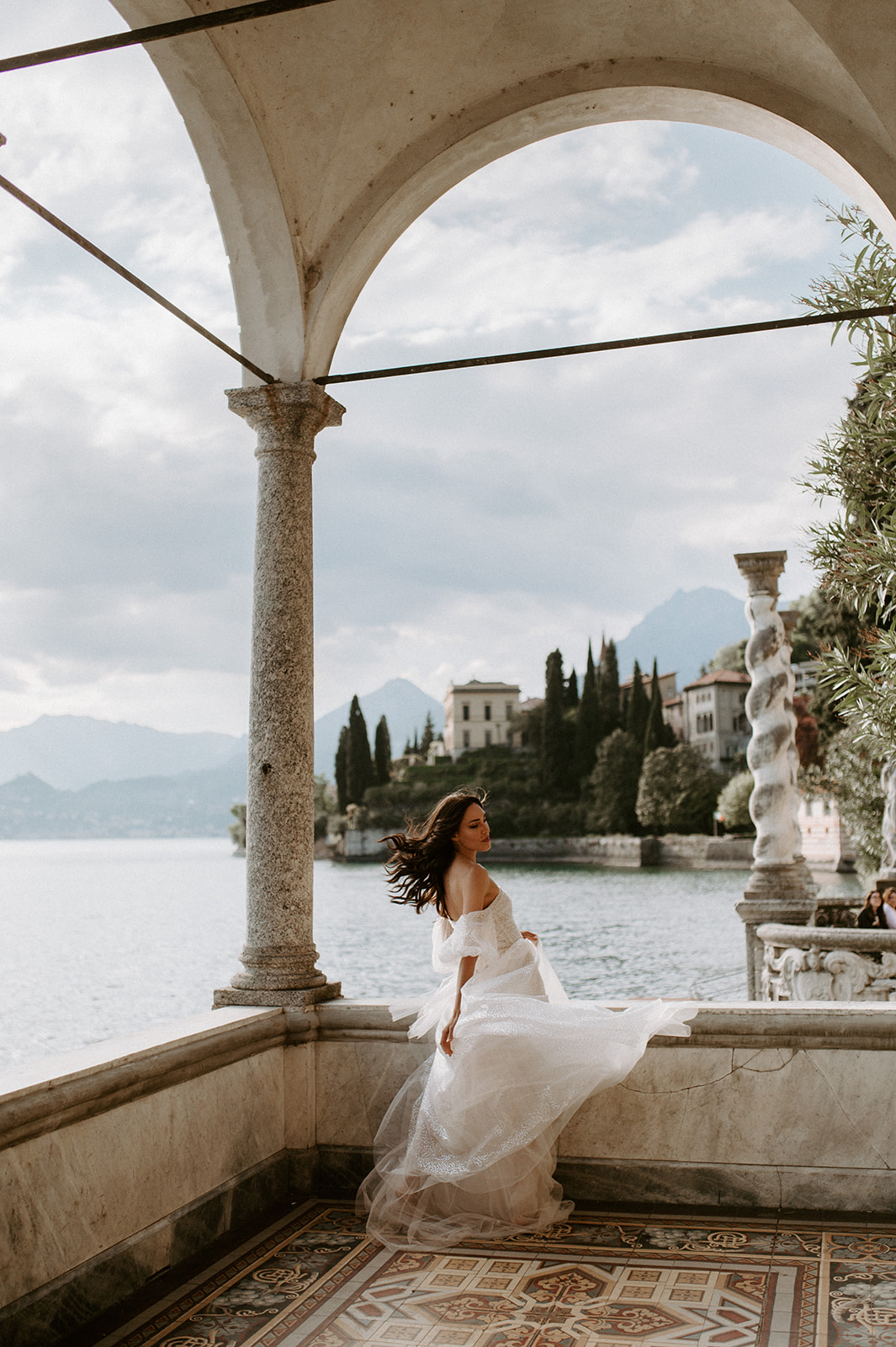 bride playing with dress jolie by berta lake Como in background