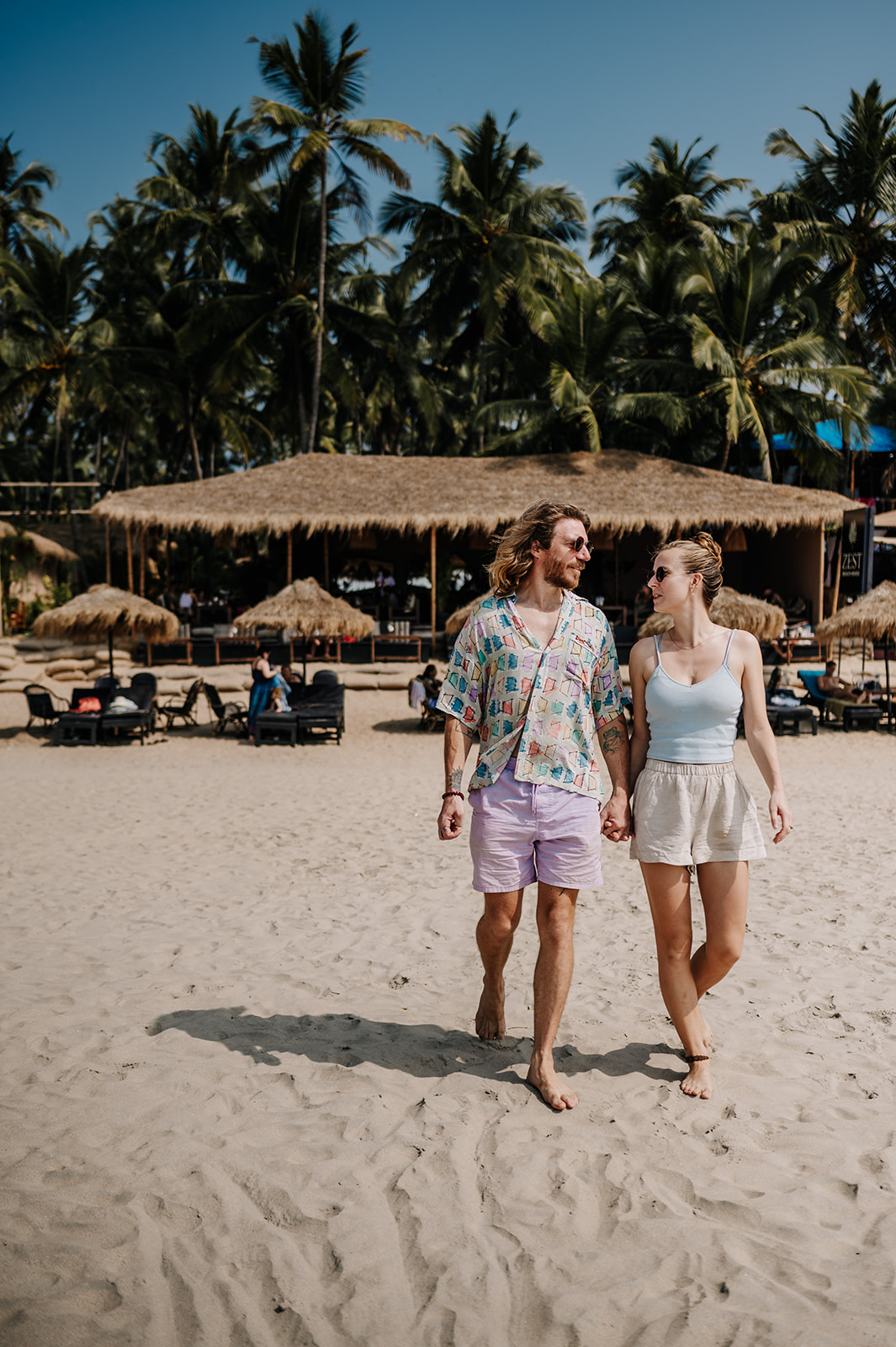 A beautiful couple with blonde hair walking along a beach in goa India 