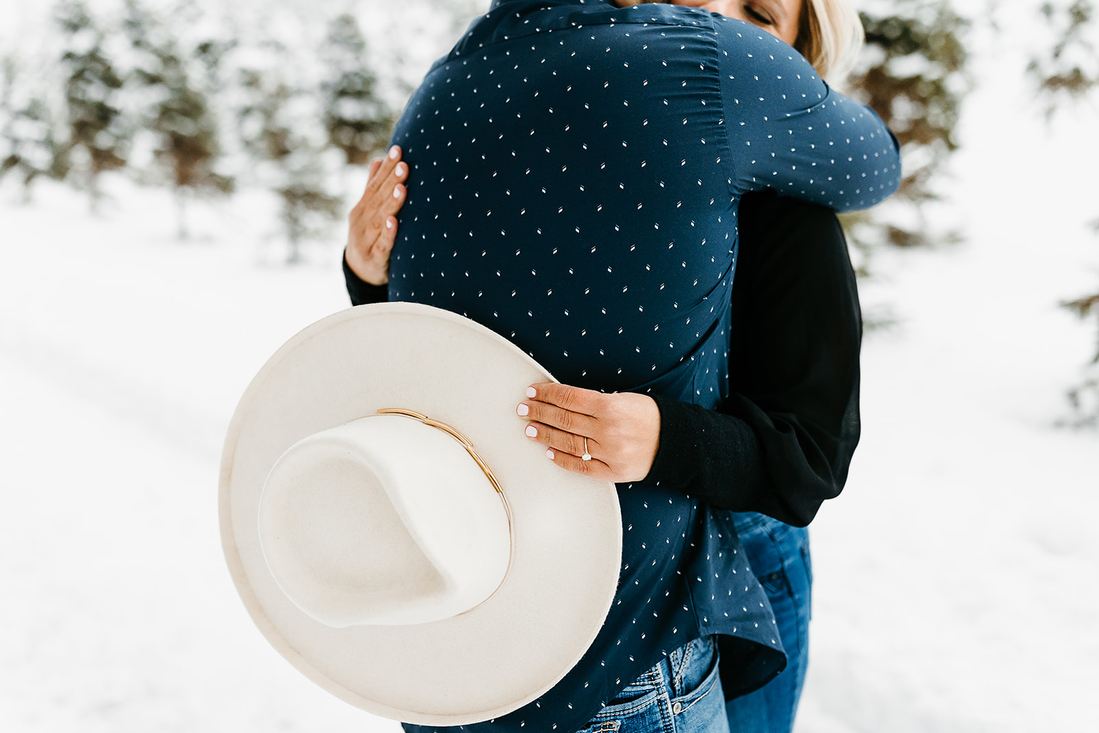 woman hugging man while holding a hat