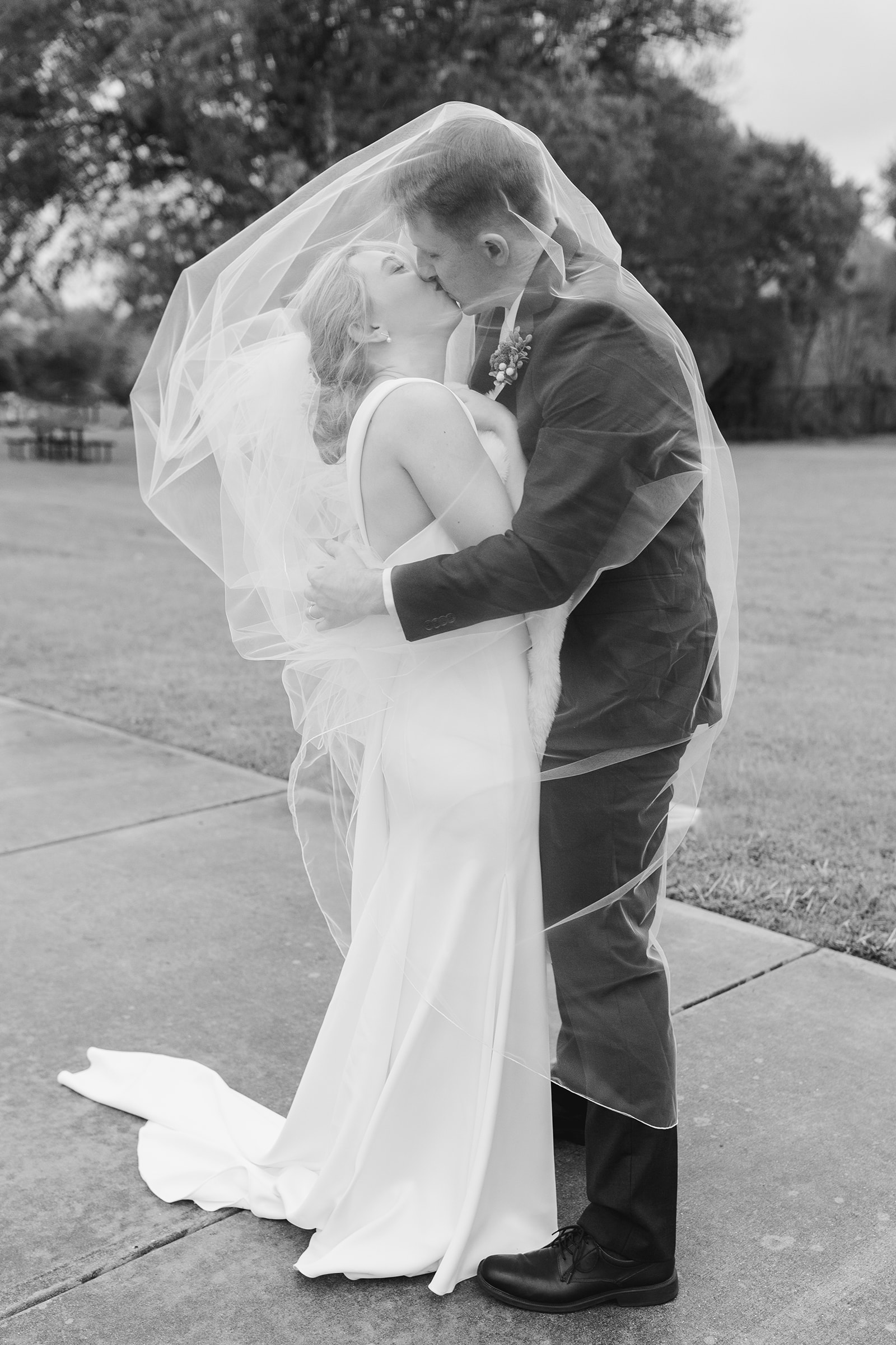 A bride and groom kissing under a veil in Austin, Texas