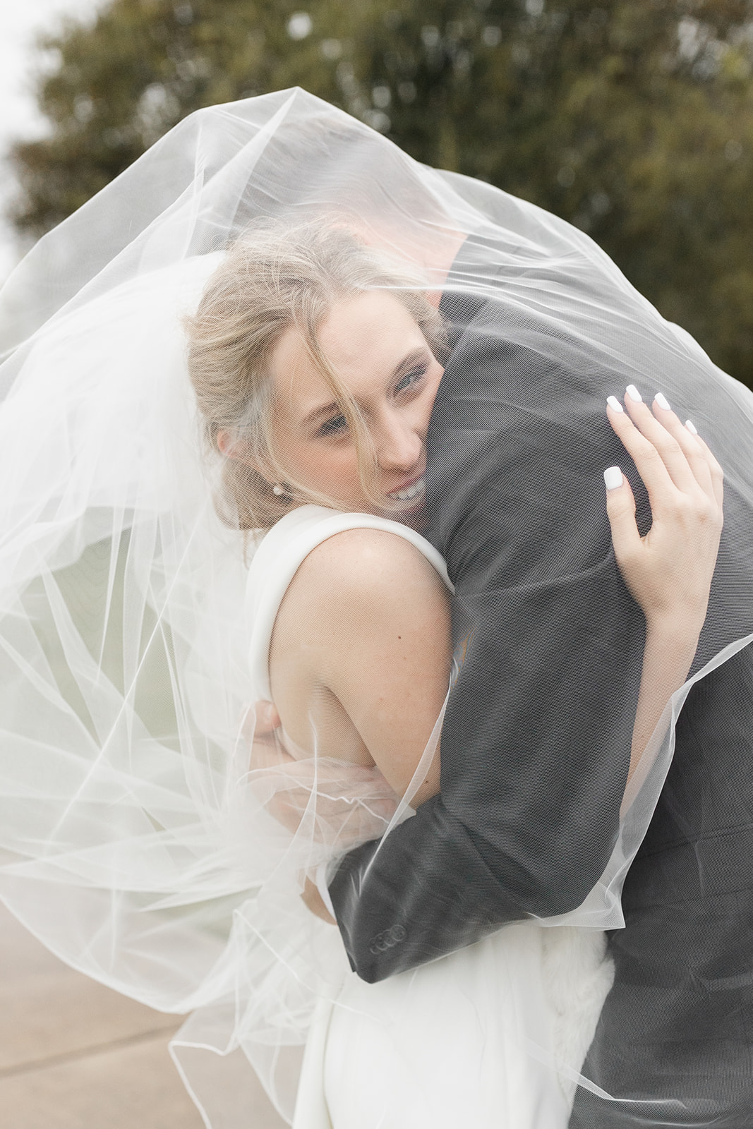 A bride and groom embracing under a veil in Austin, Texas