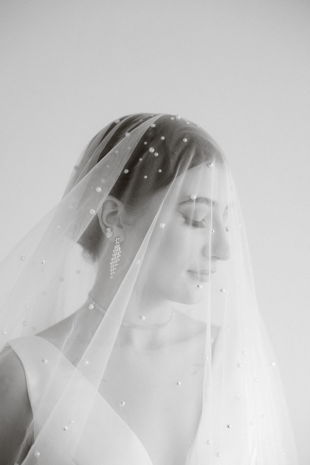 A bride with her pearl-studded cathedral veil draped over her head.