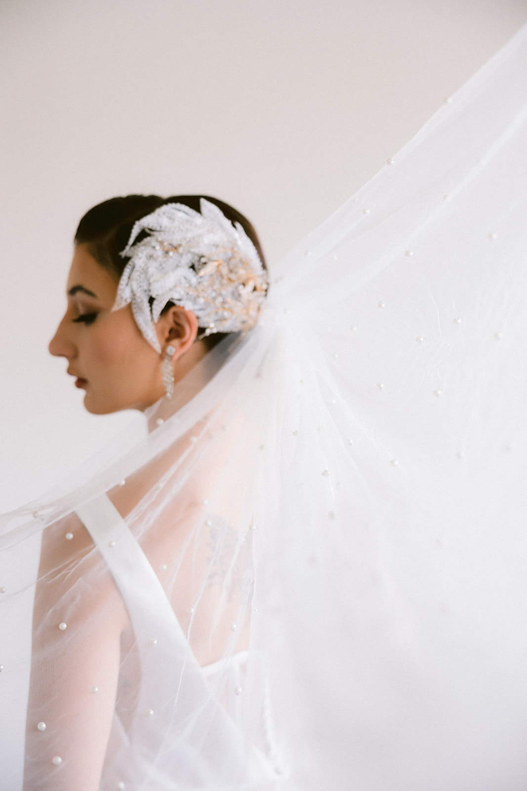 A closeup of our bride's swan lake inspired headpiece and pearl-studded veil.