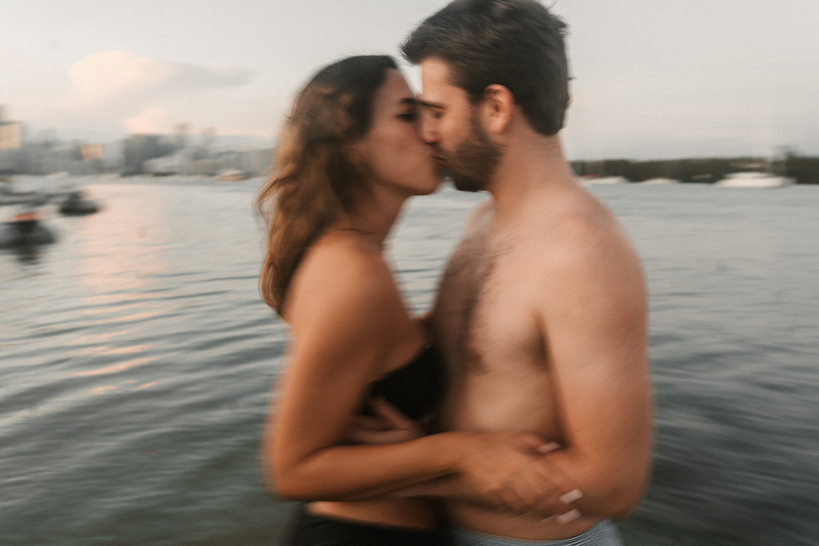 A couple kissing, blurry shot in the ocean with sunset behind them, Miami Beach, with downtown Miami skyline.