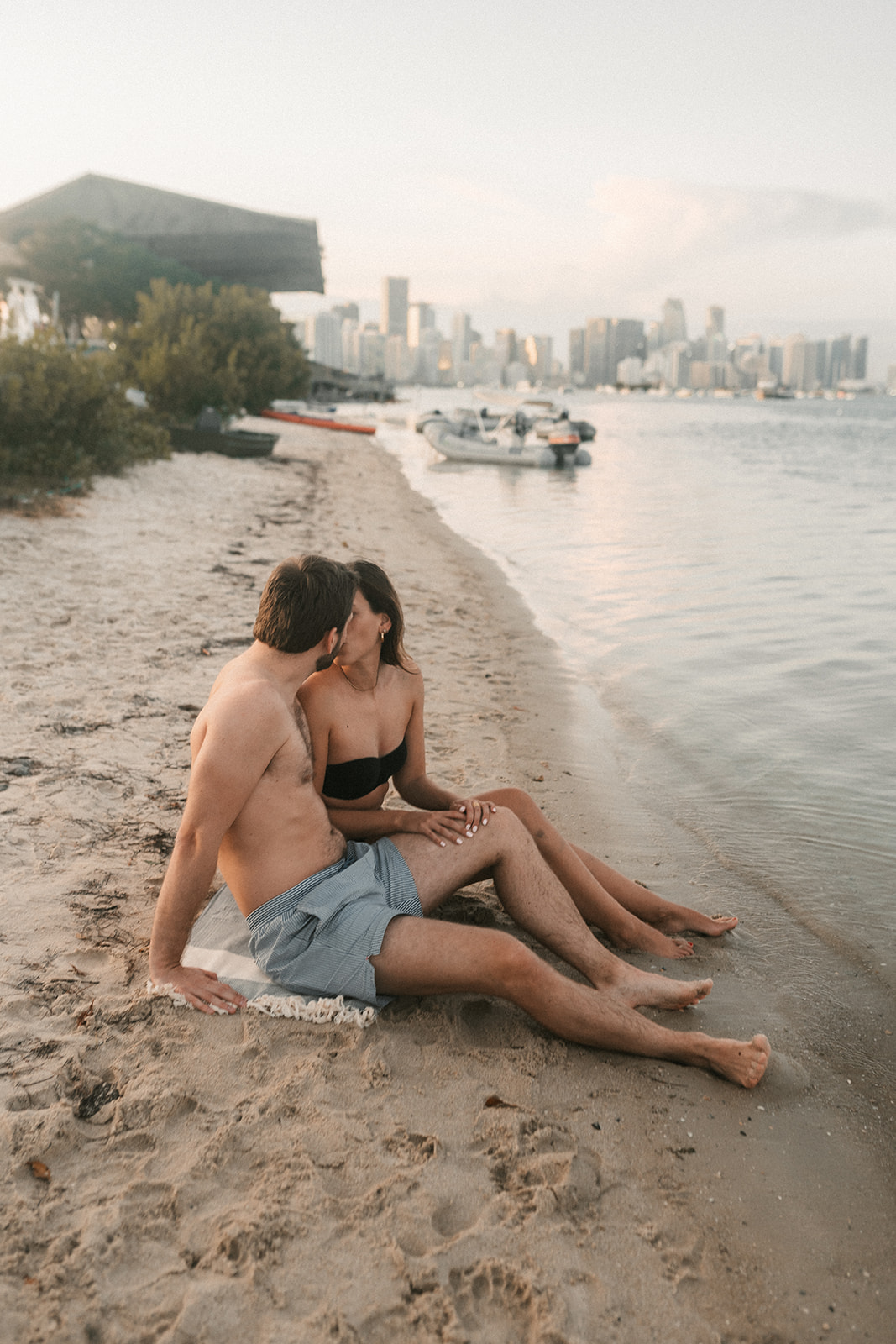 A couple kissing on the beach in Miami Beach with downtown Miami skyline.