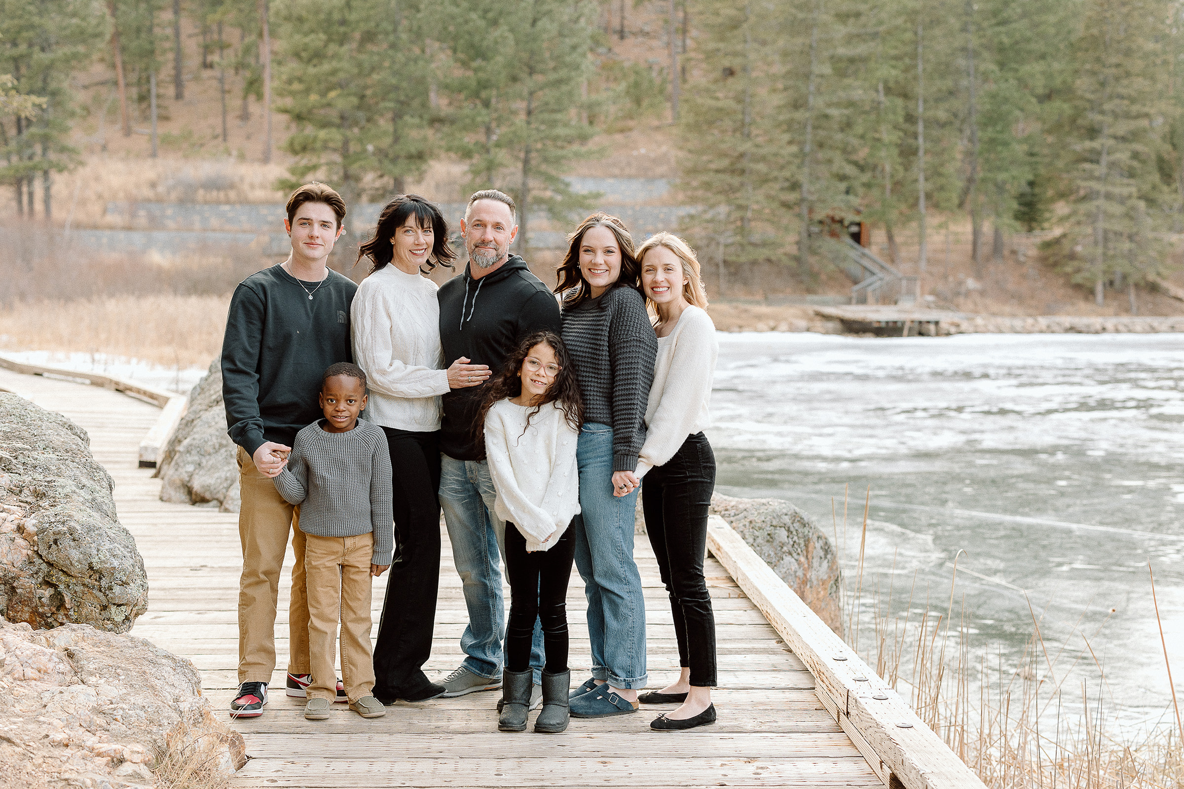 Large family standing near mountain lake