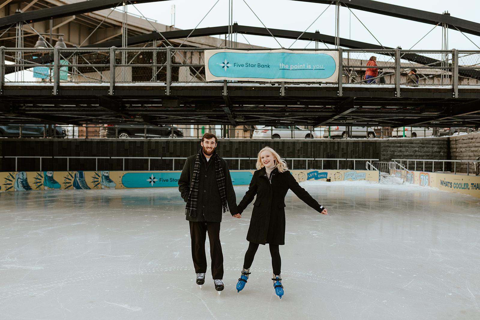 A couple doing engagement photos in Buffalo, NY skates on the ice of Canalside.