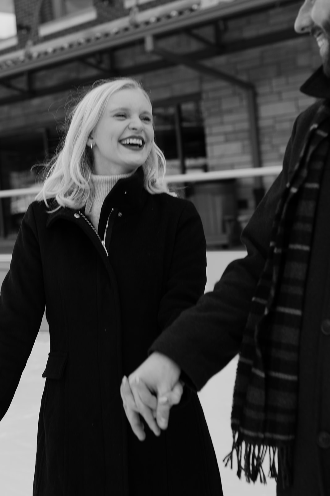 A couple laughs together while ice skating during their engagement photos in downtown Buffalo, NY.