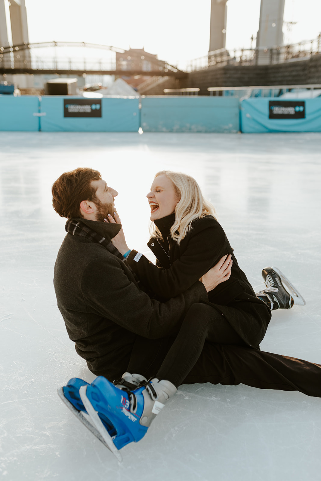 A couple laughs on the ice rink in Buffalo, NY during their engagement photo session.