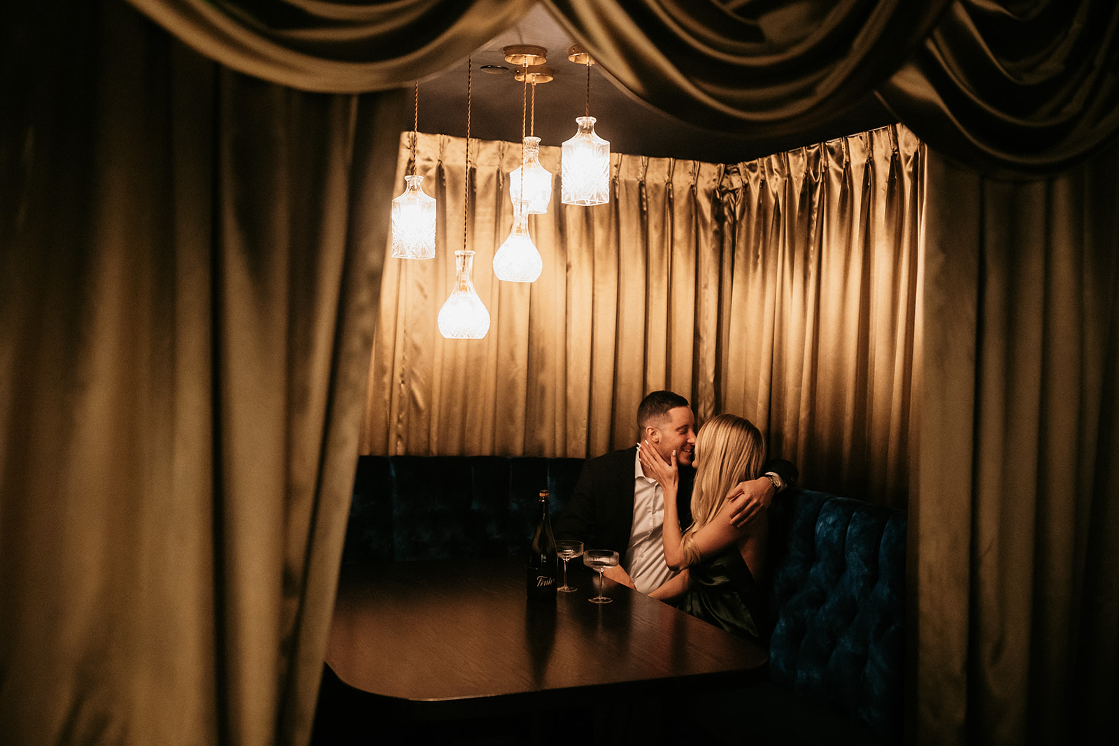 A couple shares a drink during an intimate engagement session date night in Des Moines, Iowa.