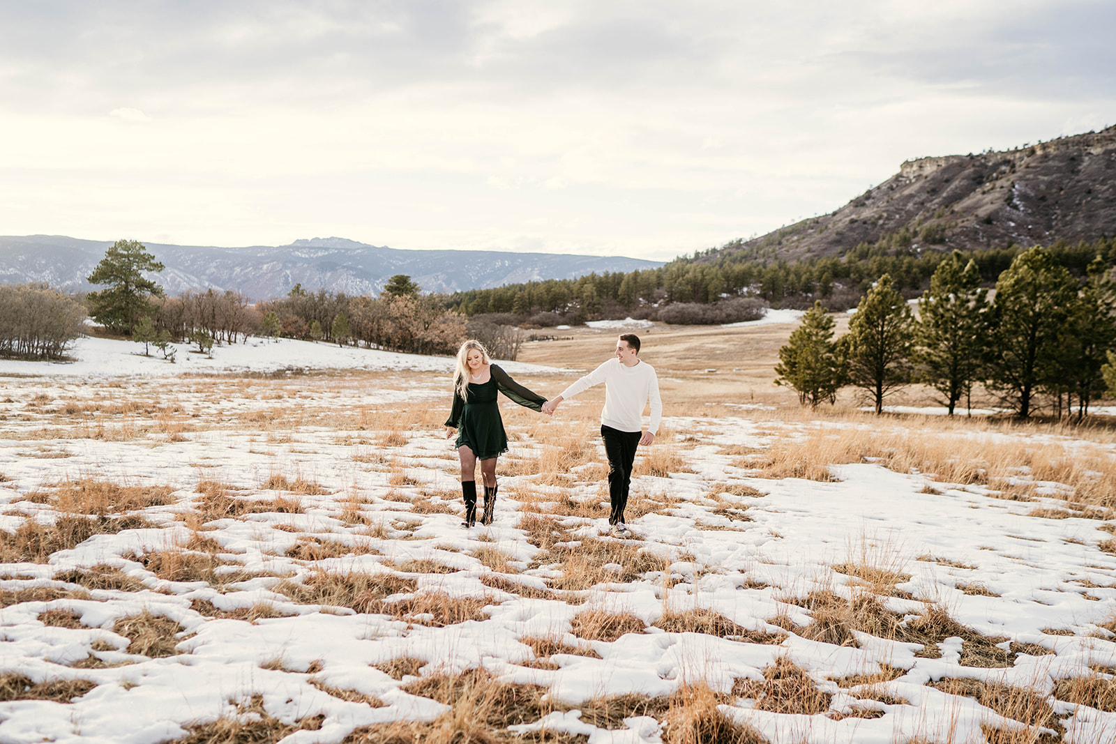 Sweet couple engagement session in grassy field with beautiful mountain views in Castle Rock, Colorado