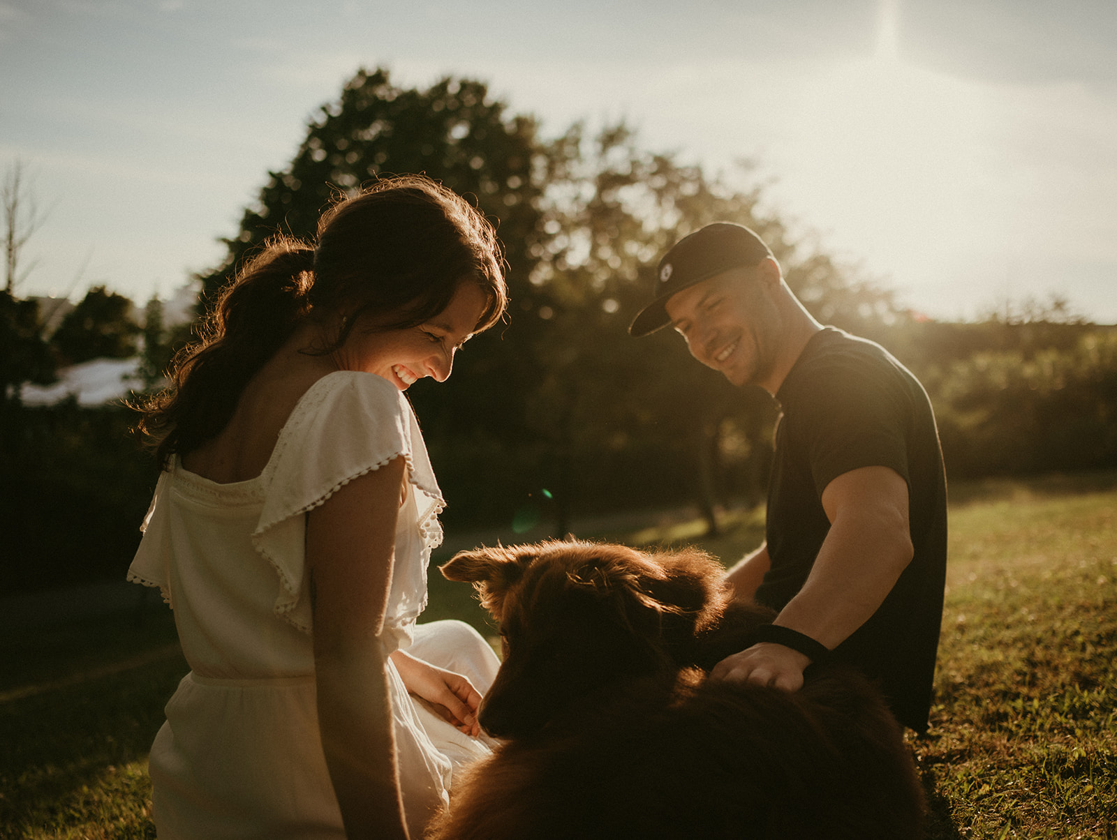 couple playing with dog during golden hour photoshoot 