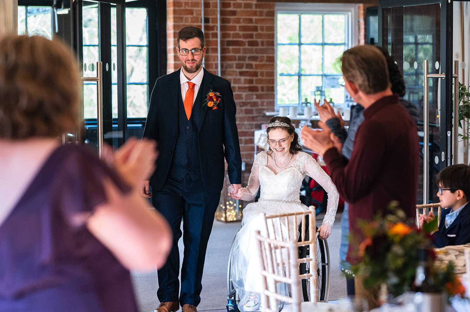 Married couple entering reception, bride in a wheelchair