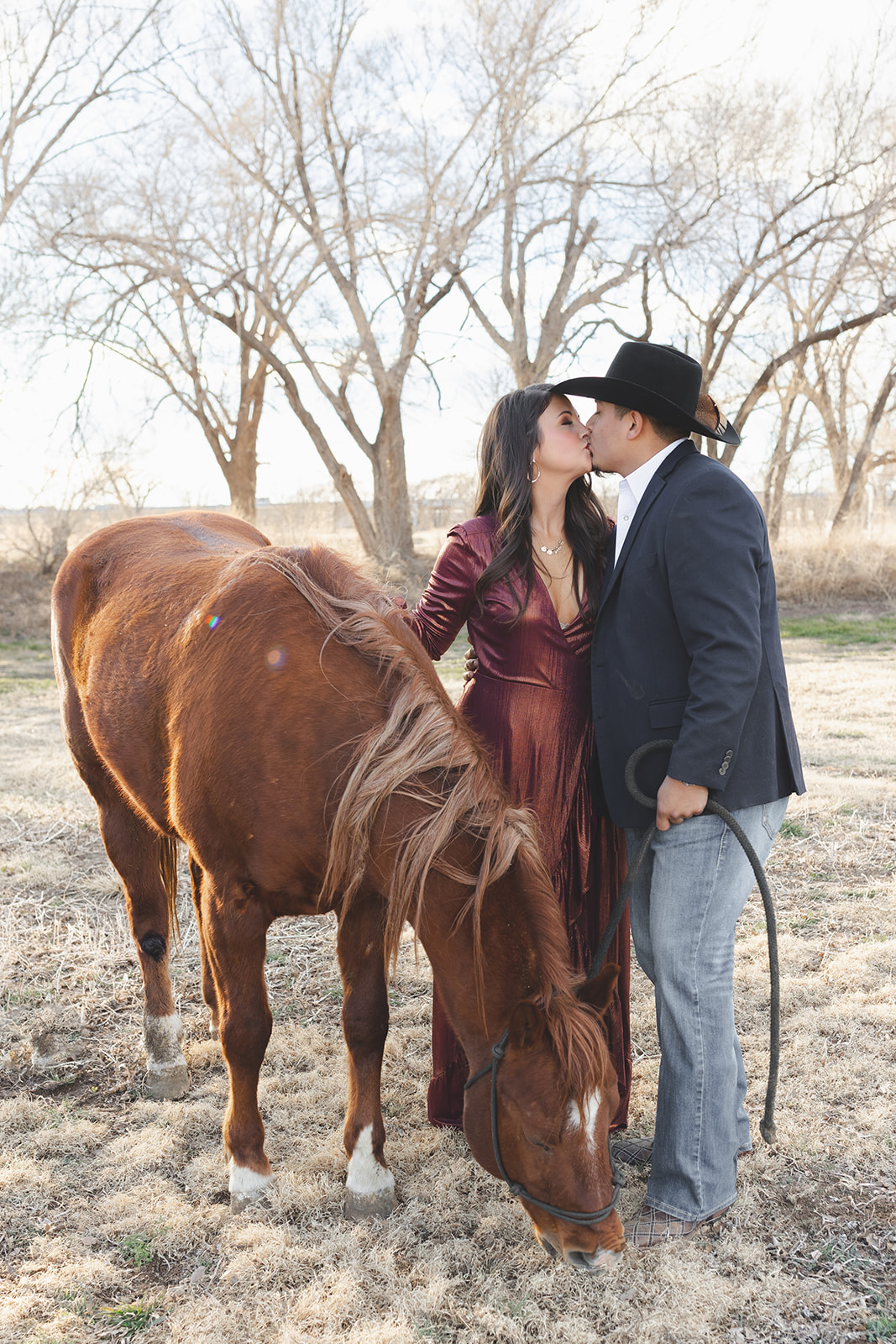 a couple kissing at their engagement session with a horse