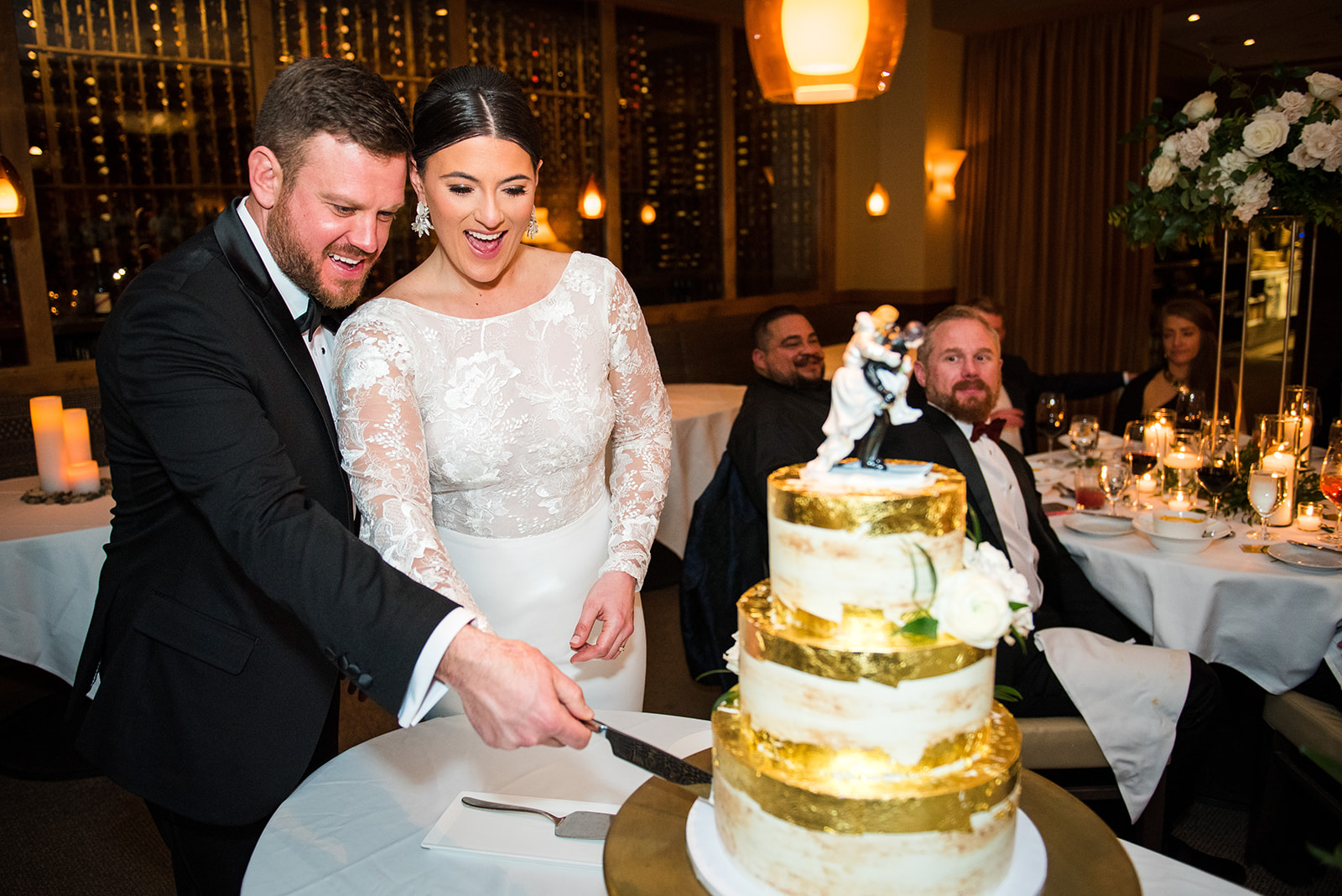 Bride and groom cut their wedding cake with smiling faces.