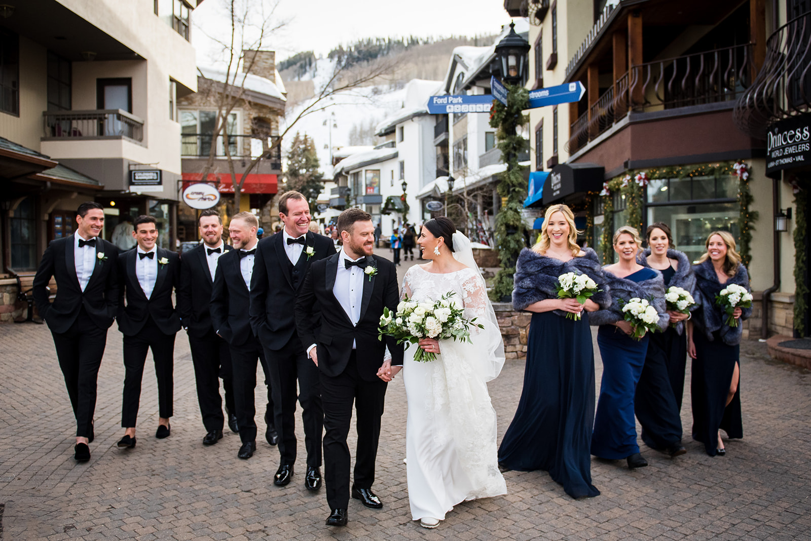 Bride and groom lead their wedding party walking through Vail Village in Colorado.